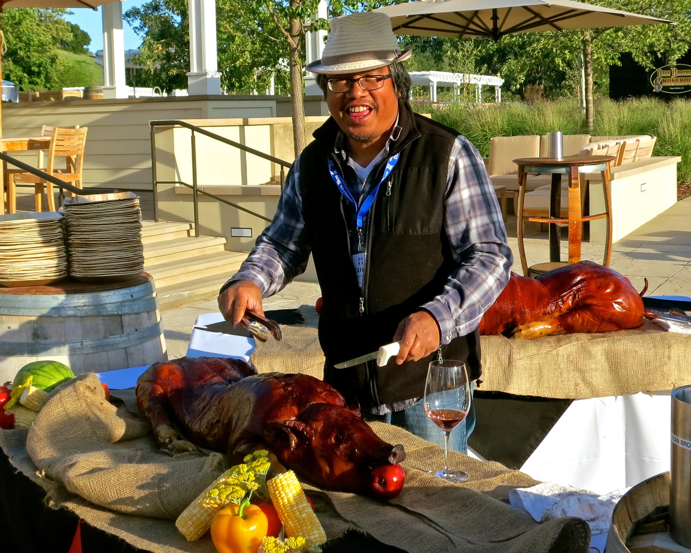 Smiling man preparing roasted pig at Lodi Winegrape Commission outdoor event.