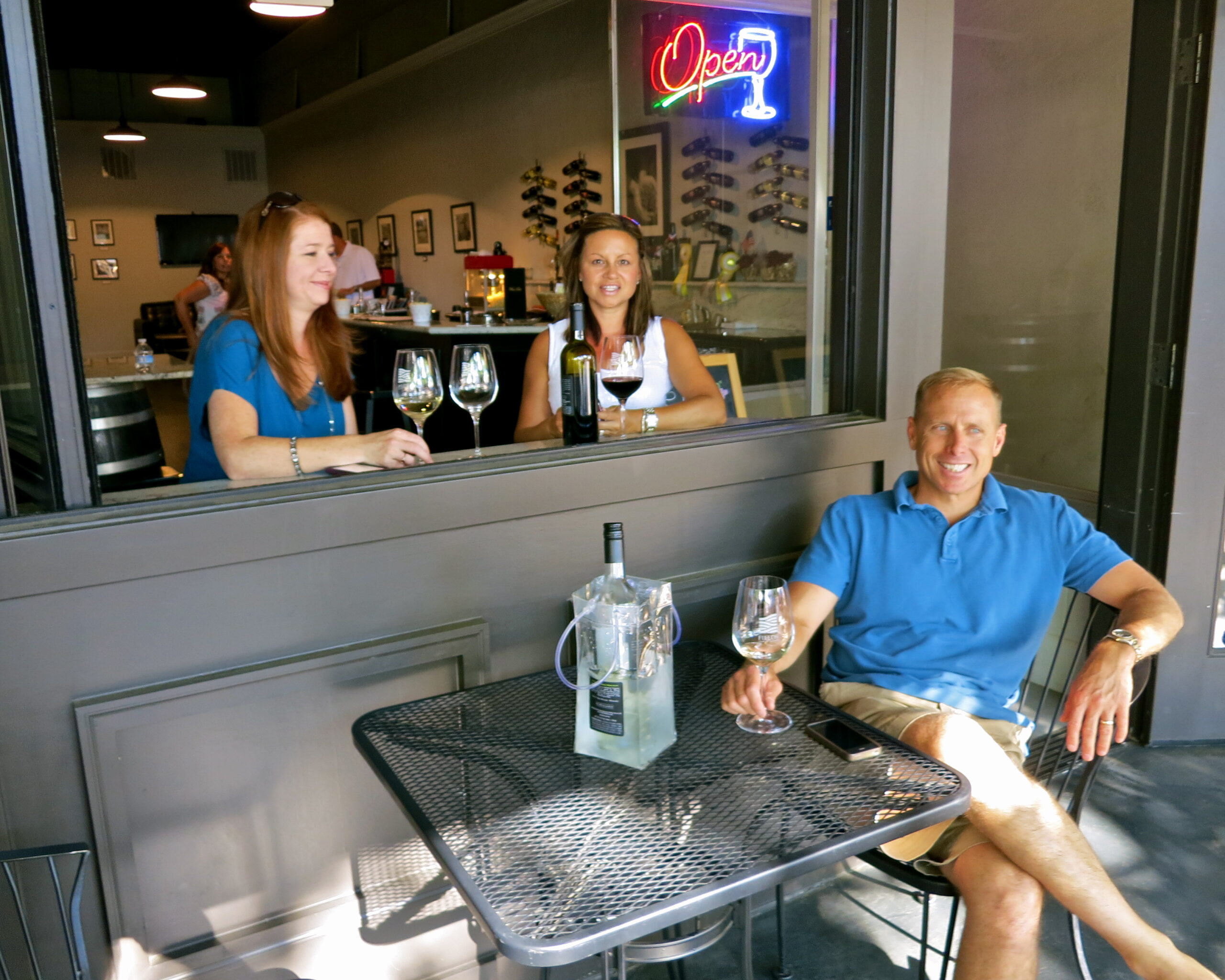 People enjoying wine tasting at a Lodi winery with glasses and a bottle on the table.