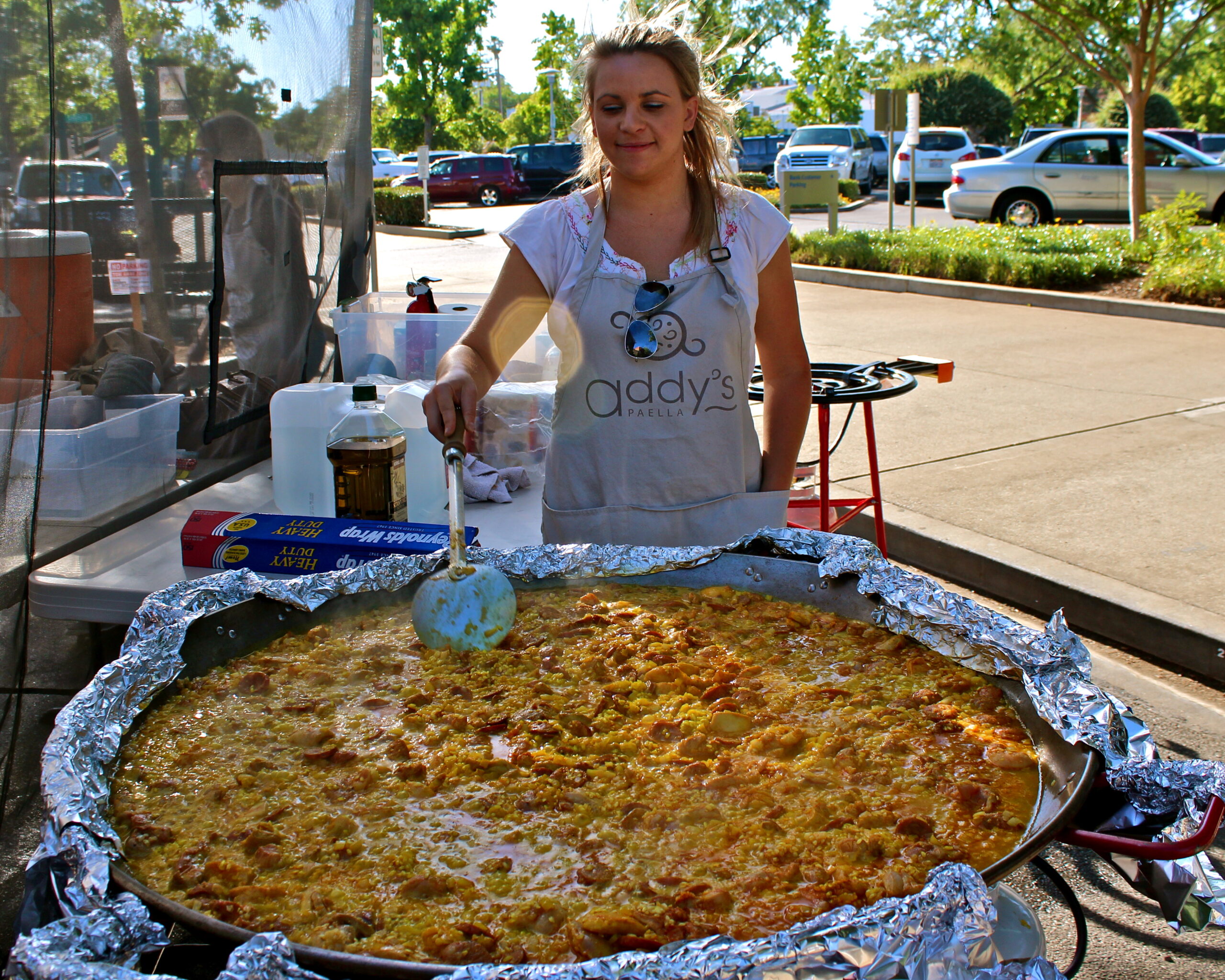Young woman preparing a giant pizza at a Lodi Winegrape Commission event outdoors.