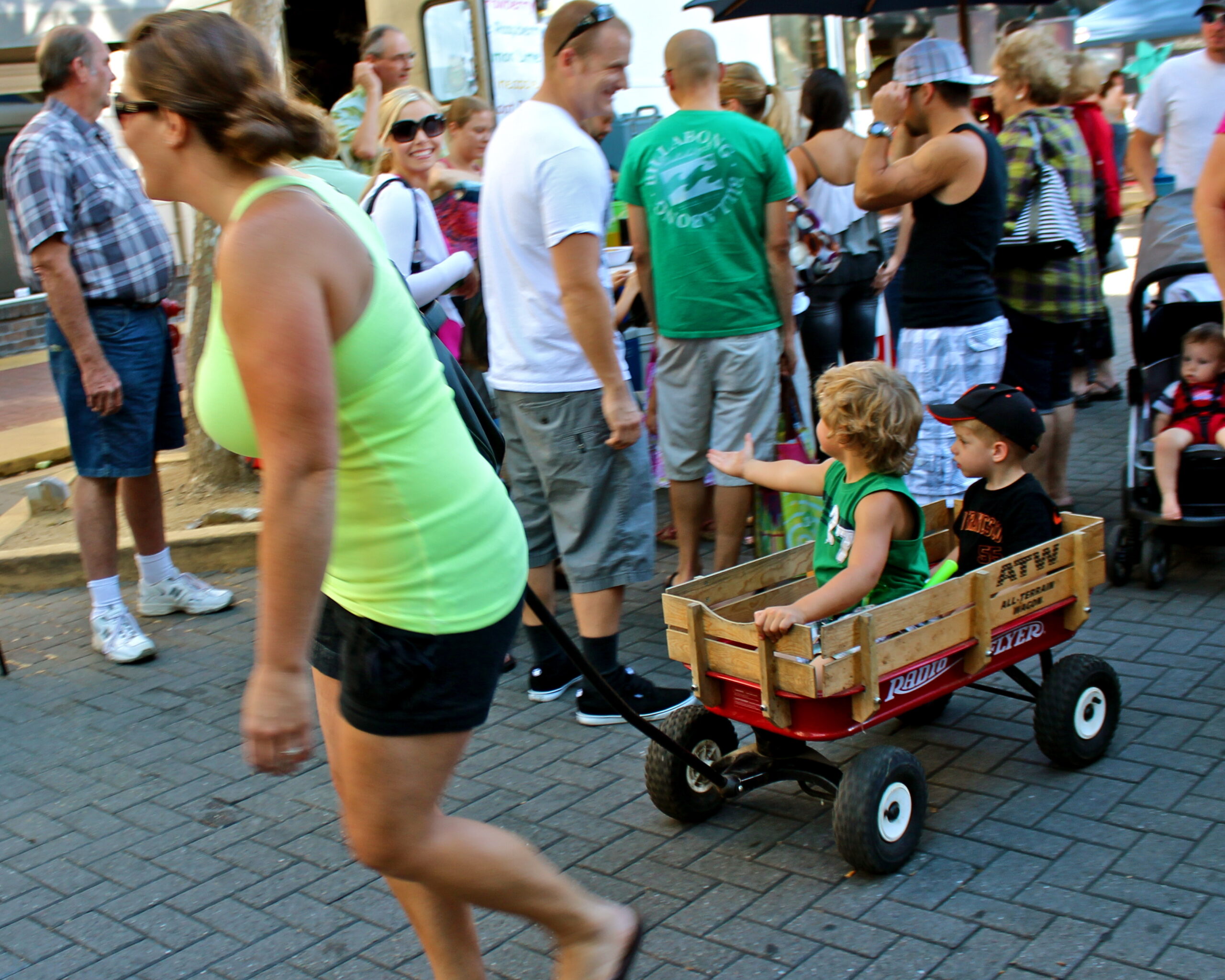 Crowd of people at Lodi Winegrape Commission event with children in wagon.