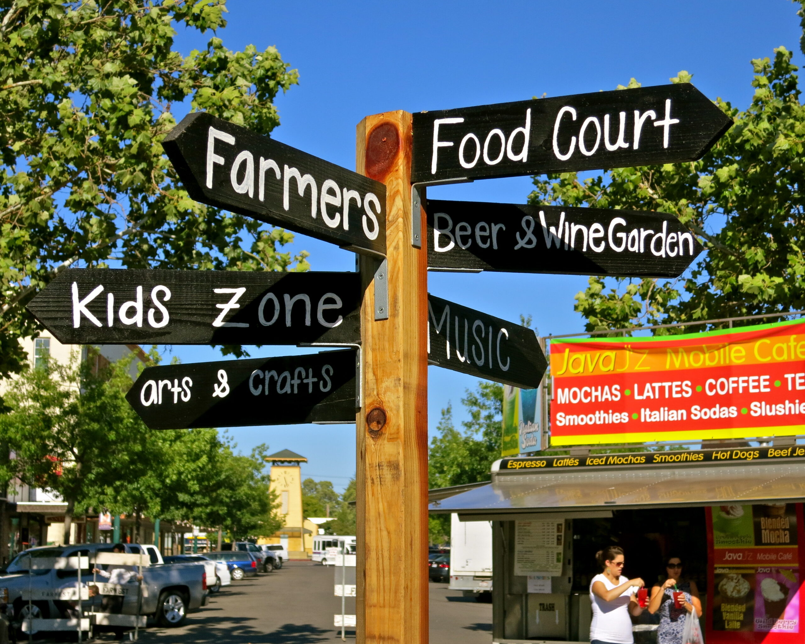 Signpost with directions to food court, farmers, kids zone, music, and wine garden at Lodi event.