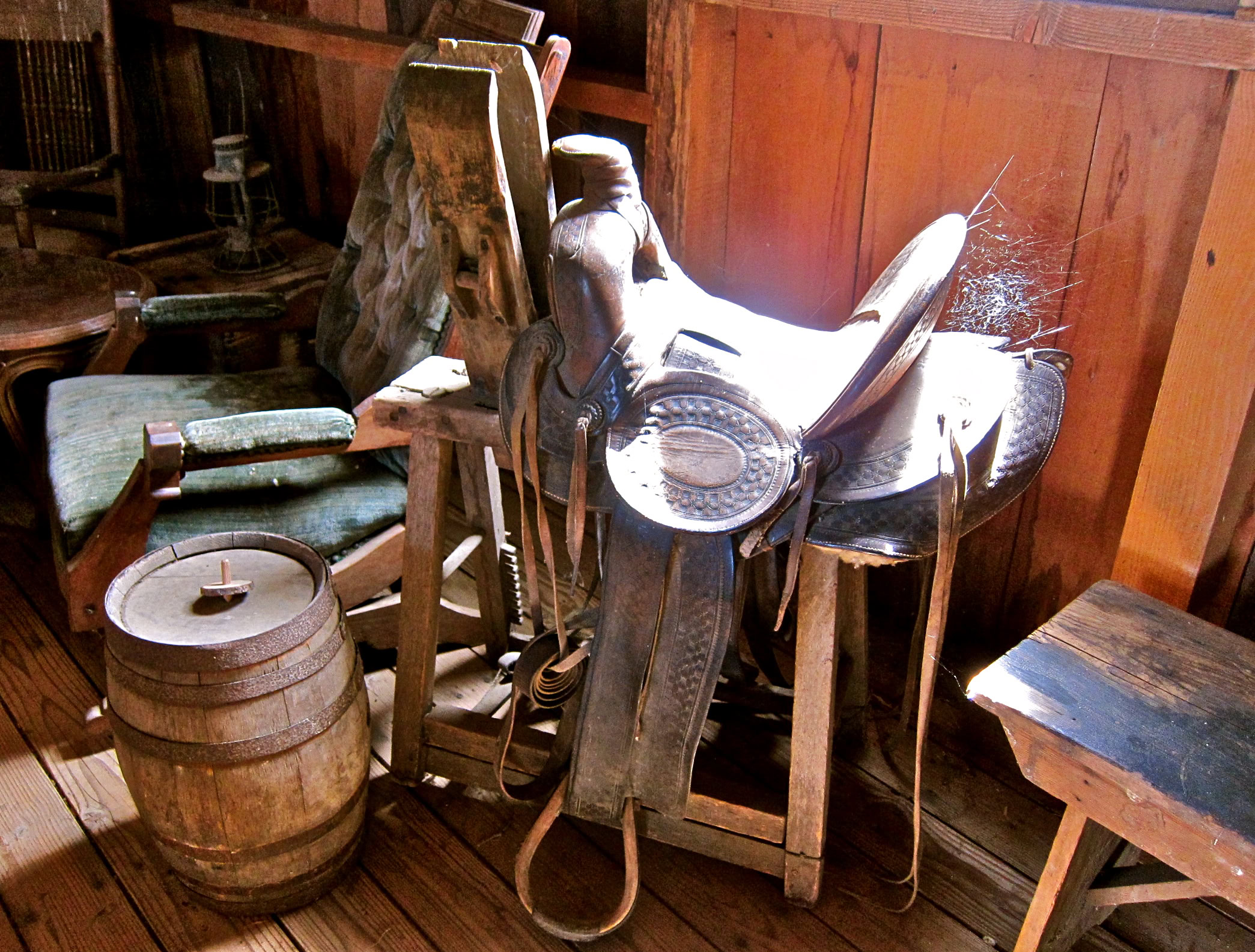 Antique saddles and wooden barrels in a rustic winery setting in Lodi, California.