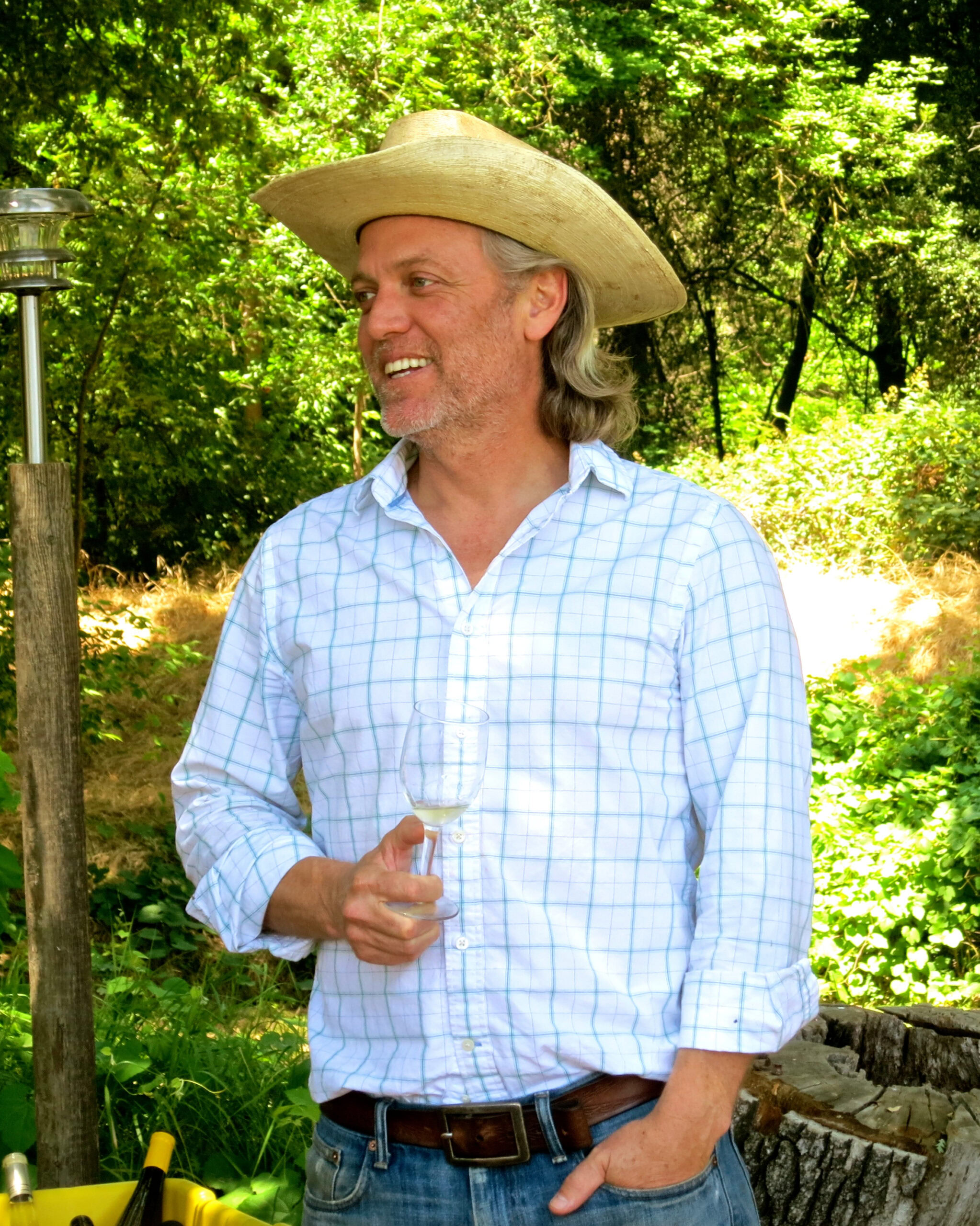Man in a cowboy hat holding a glass of wine outdoors at a Lodi wine event.