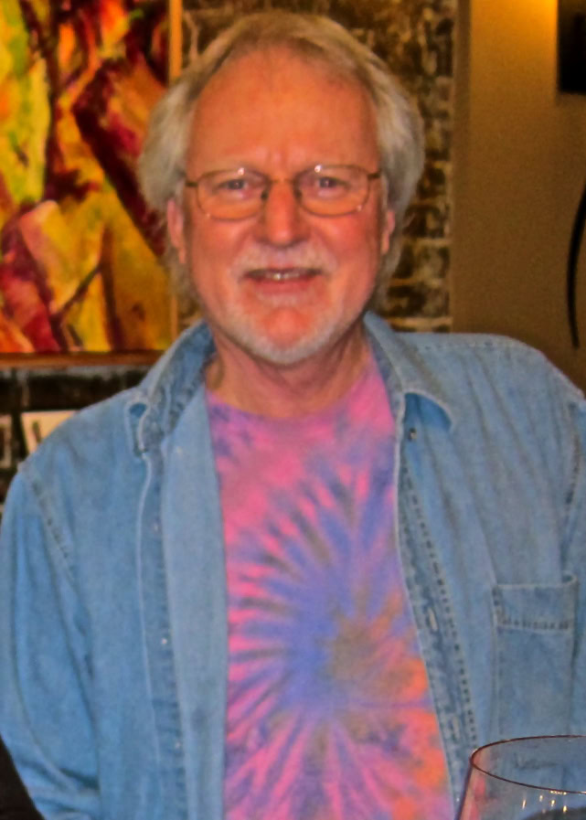 Older man with glasses, tie-dye shirt, and denim jacket at Lodi wine event.