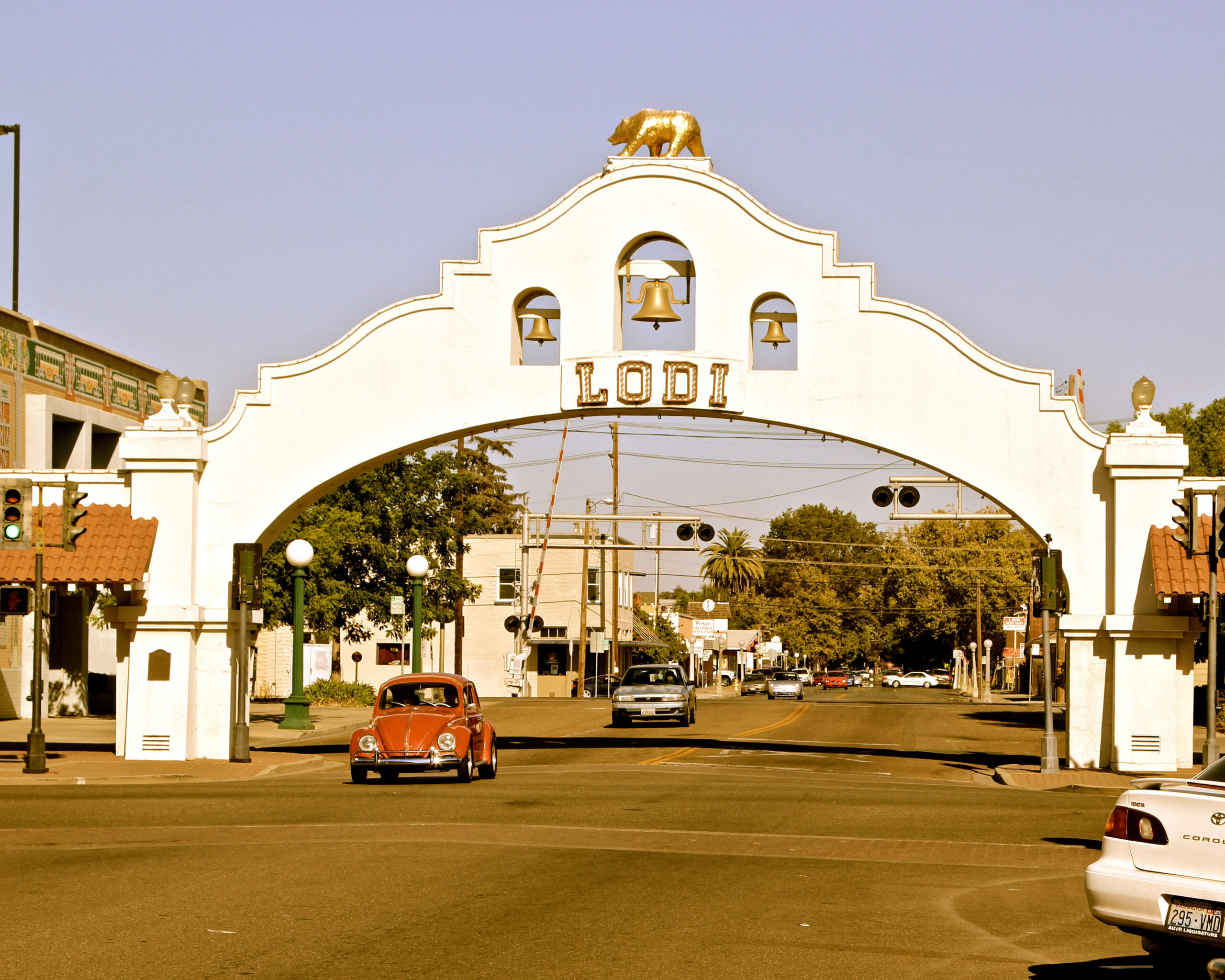 Lodi Winegrape Commission entrance arch with a golden bear on top and vintage cars passing underneath.