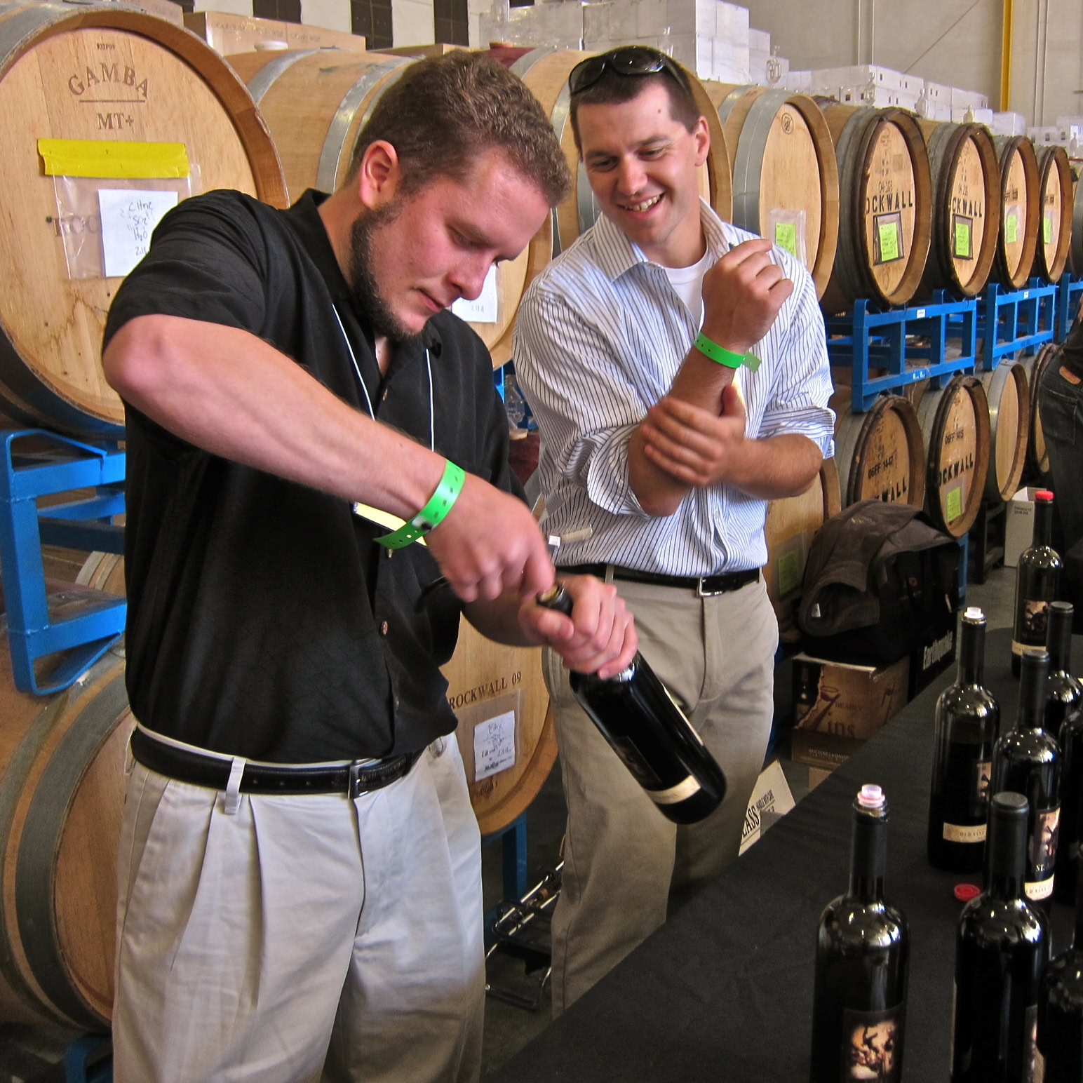 Two men tasting wine at a Lodi wine event with barrels in the background.
