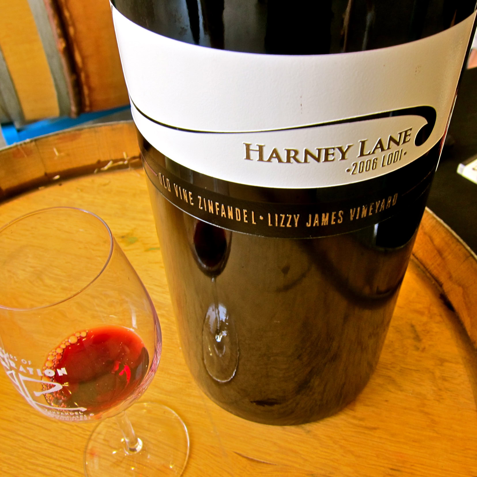 Close-up of a Harney Lane wine bottle and glass on a wooden surface, showcasing wine tasting experience.