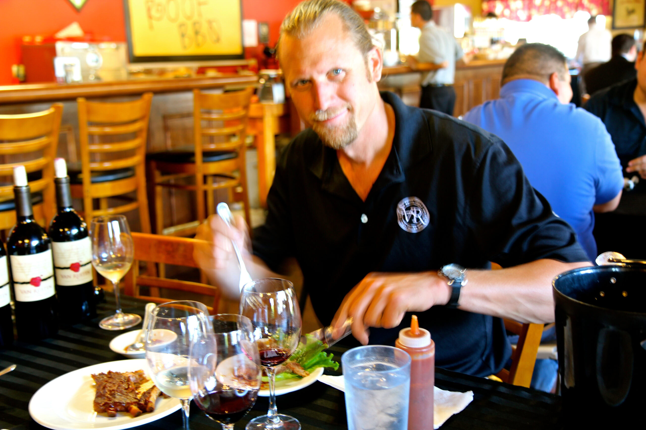 Man enjoying wine tasting at Lodi Winegrape Commission event with wine bottles and glasses on table.