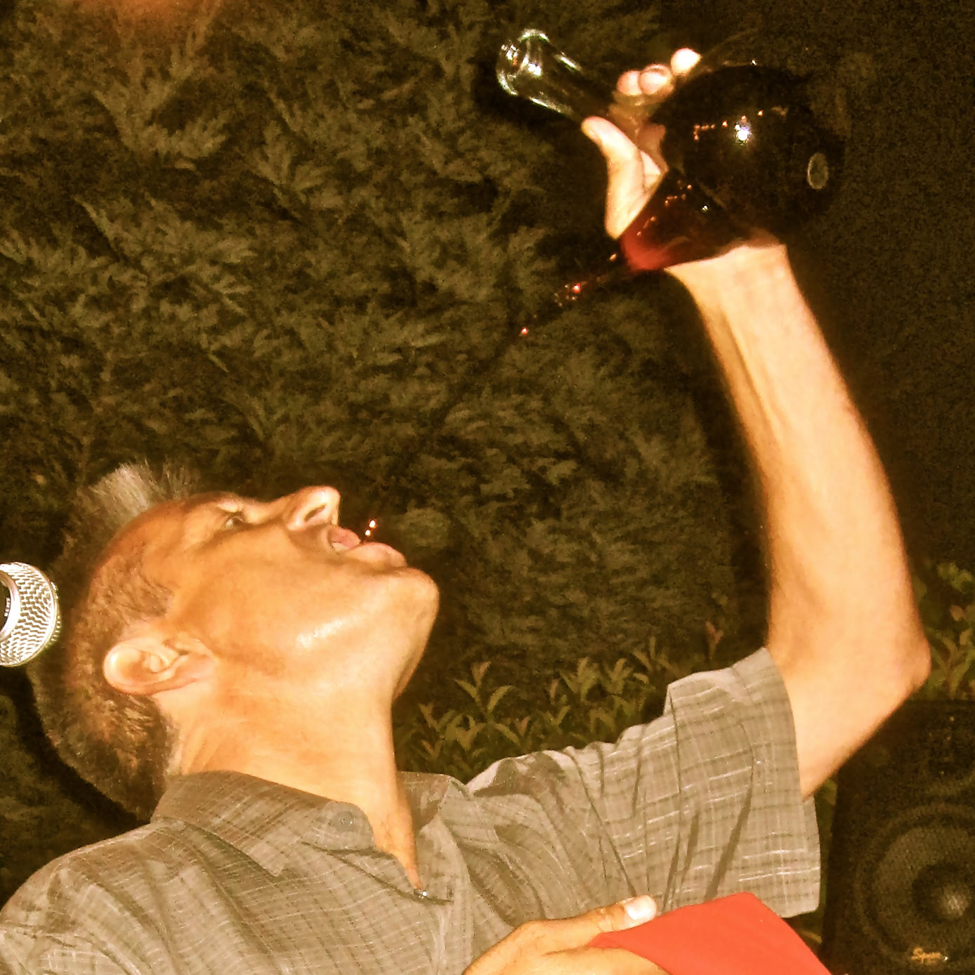 Person drinking red wine outdoors at night, celebrating with a glass of wine in hand.
