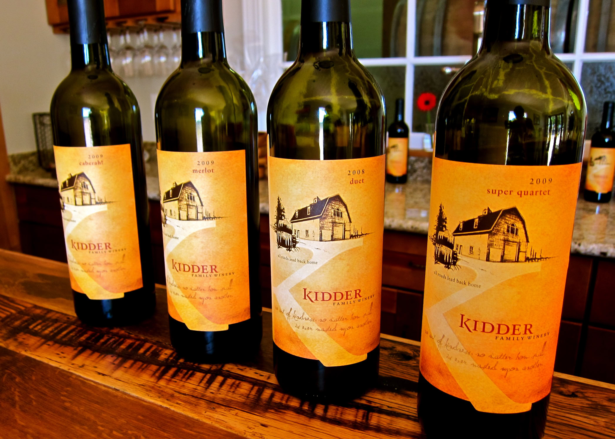 Four bottles of wine from the Lodi Winegrape Commission on a wooden table.