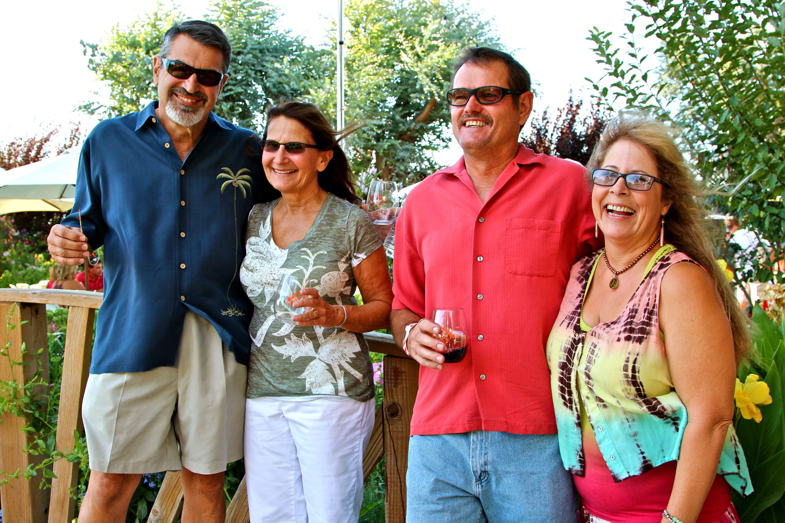 Group of four people enjoying wine outdoors at a Lodi wine event, smiling and holding glasses.