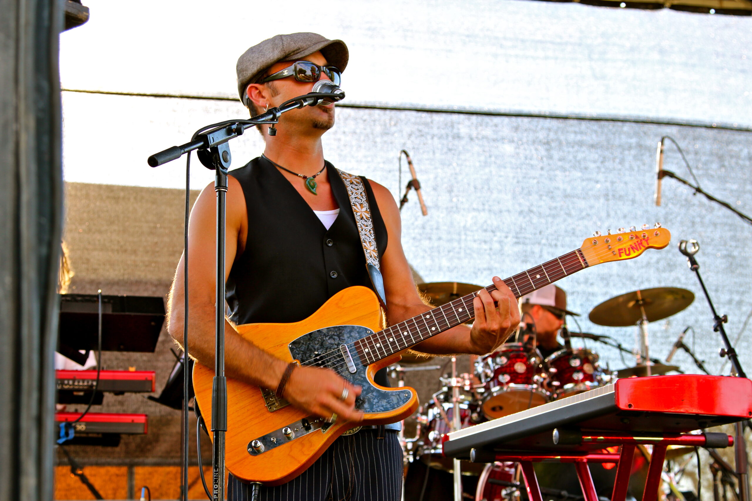 Musician playing electric guitar at Lodi Winegrape Commission event with band in background.