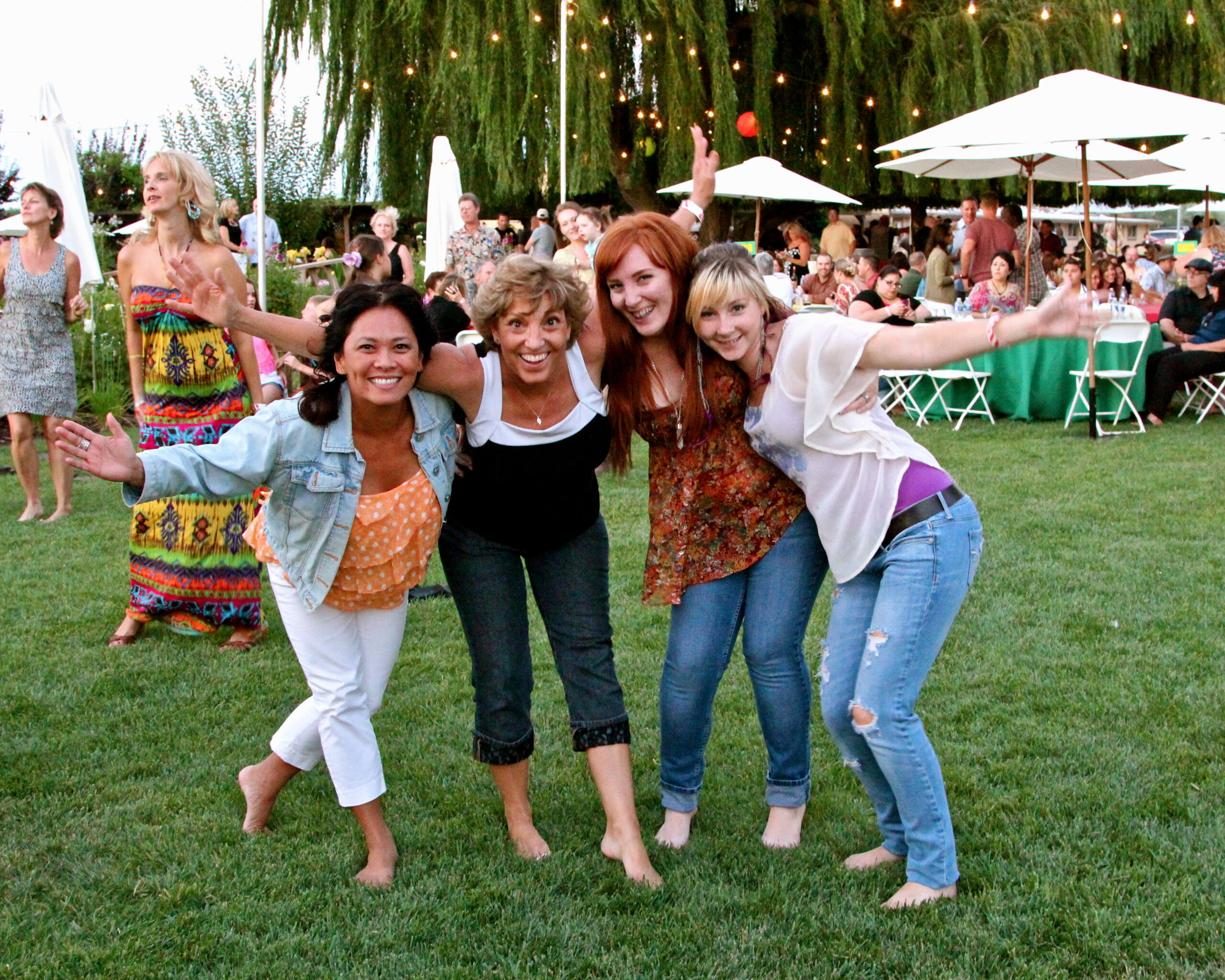 Group of women enjoying outdoor event at Lodi Winegrape Commission with festive atmosphere and string lights.
