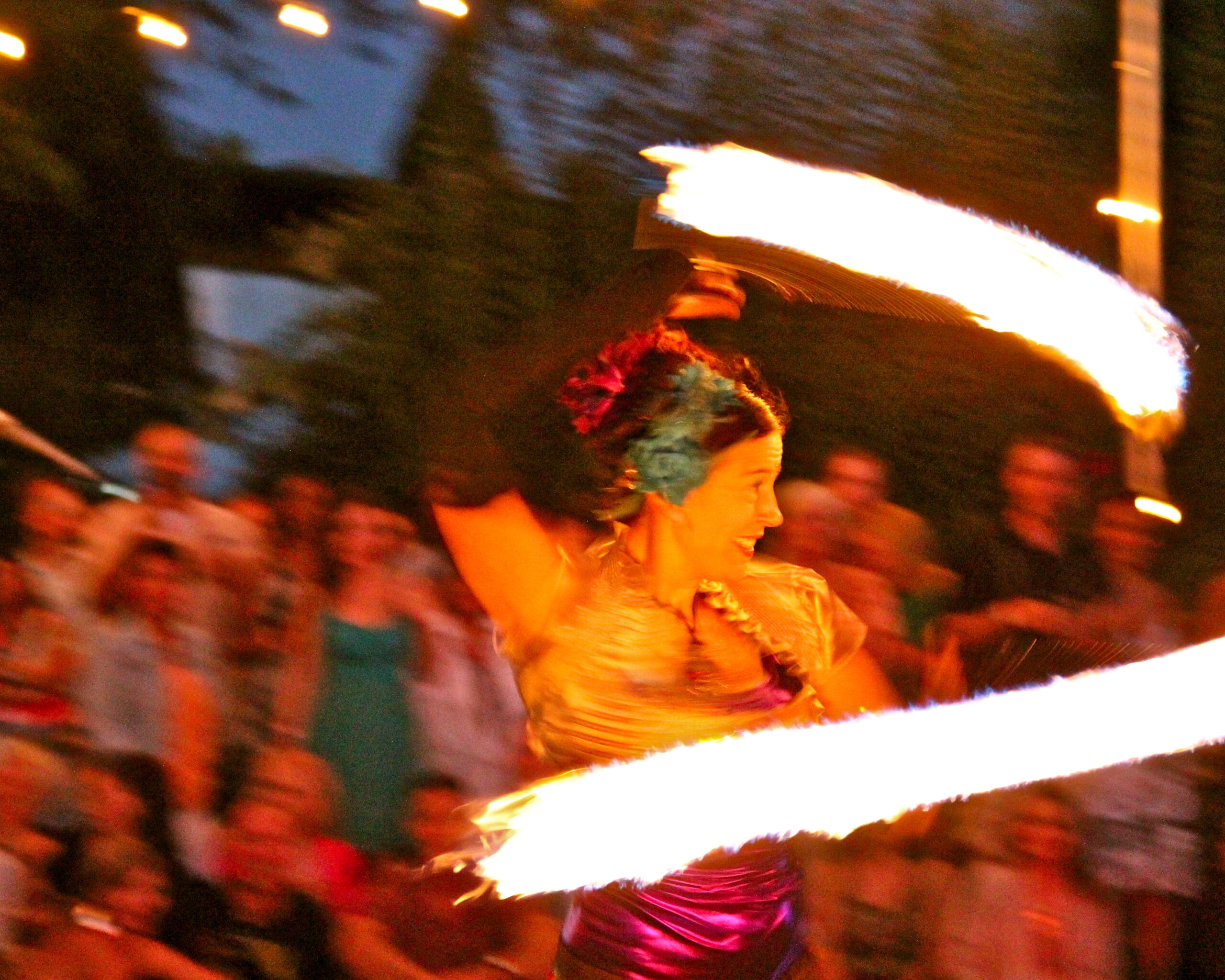Performer with fire poi at Lodi Winegrape Commission event, vibrant flames and lively crowd, evening outdoor setting.