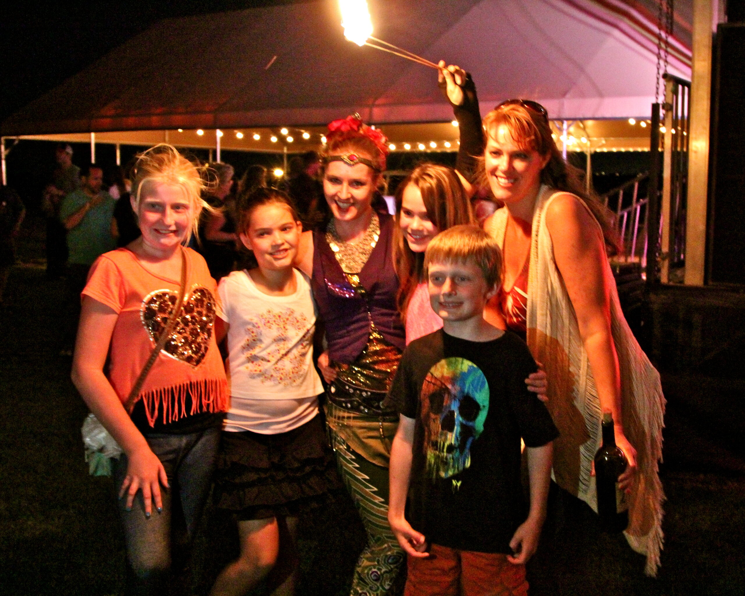 Family enjoying a night at a Lodi wine event with a sparkler and festive atmosphere.