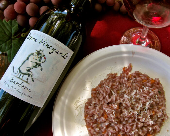 Bottle of Barbera wine from Lodi Winegrape Commission with glass of rosé and risotto dish.