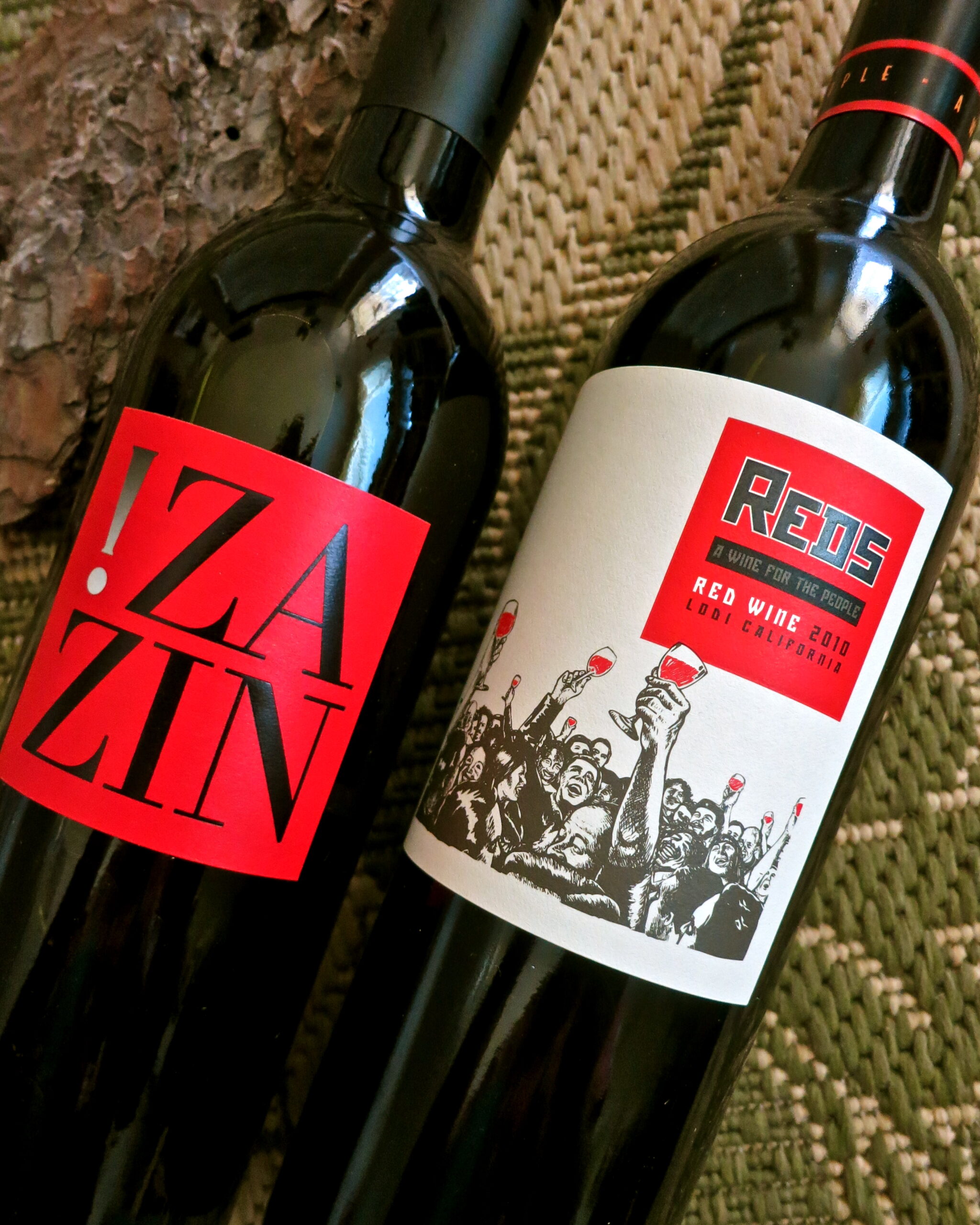 Two bottles of red wine from Lodi Winegrape Commission with vibrant labels on a textured surface.