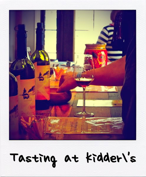 People tasting wine at a Lodi wine event with bottles and glasses on a wooden table.