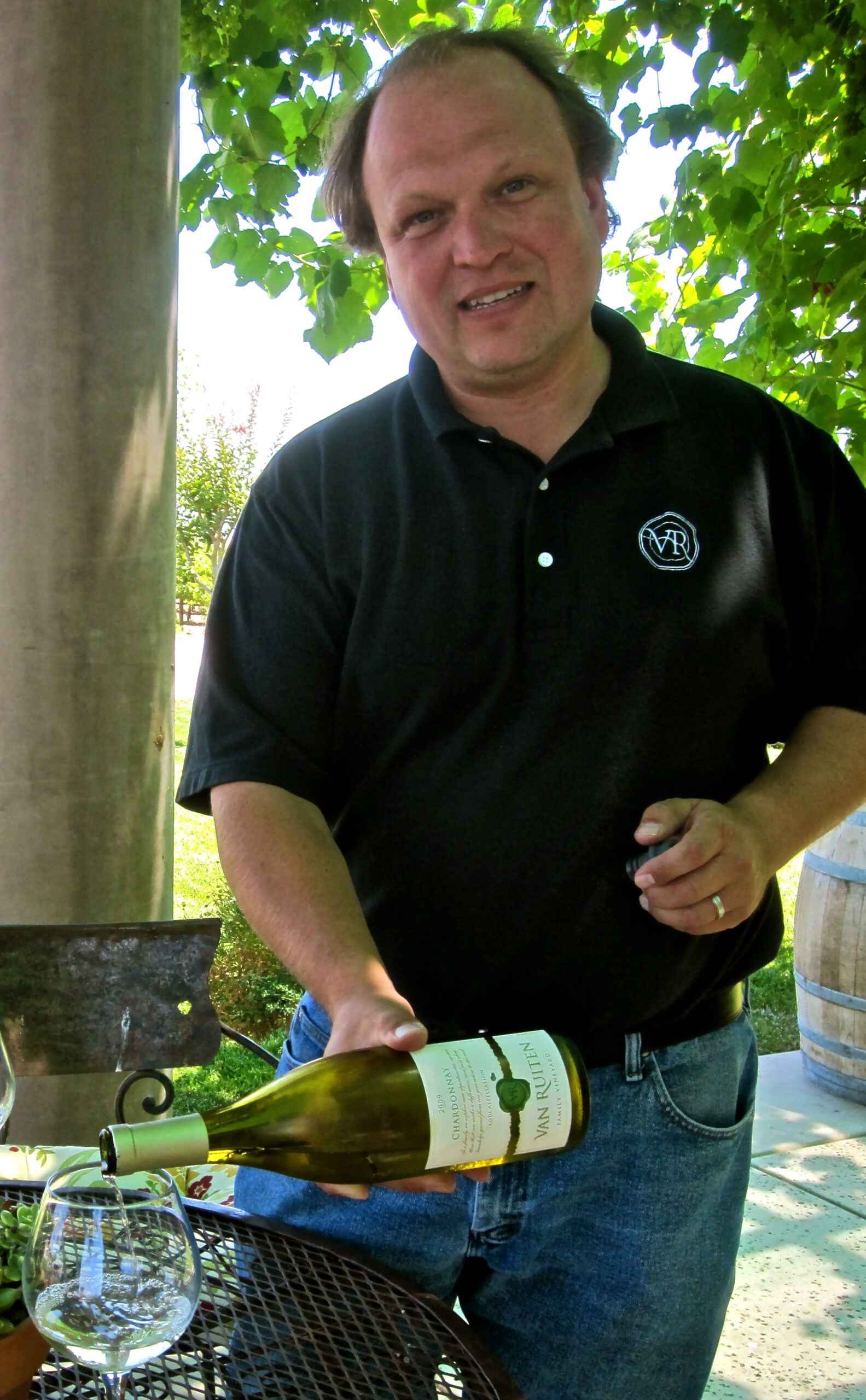 Man holding a wine bottle at a Lodi Winegrape Commission event outdoors.