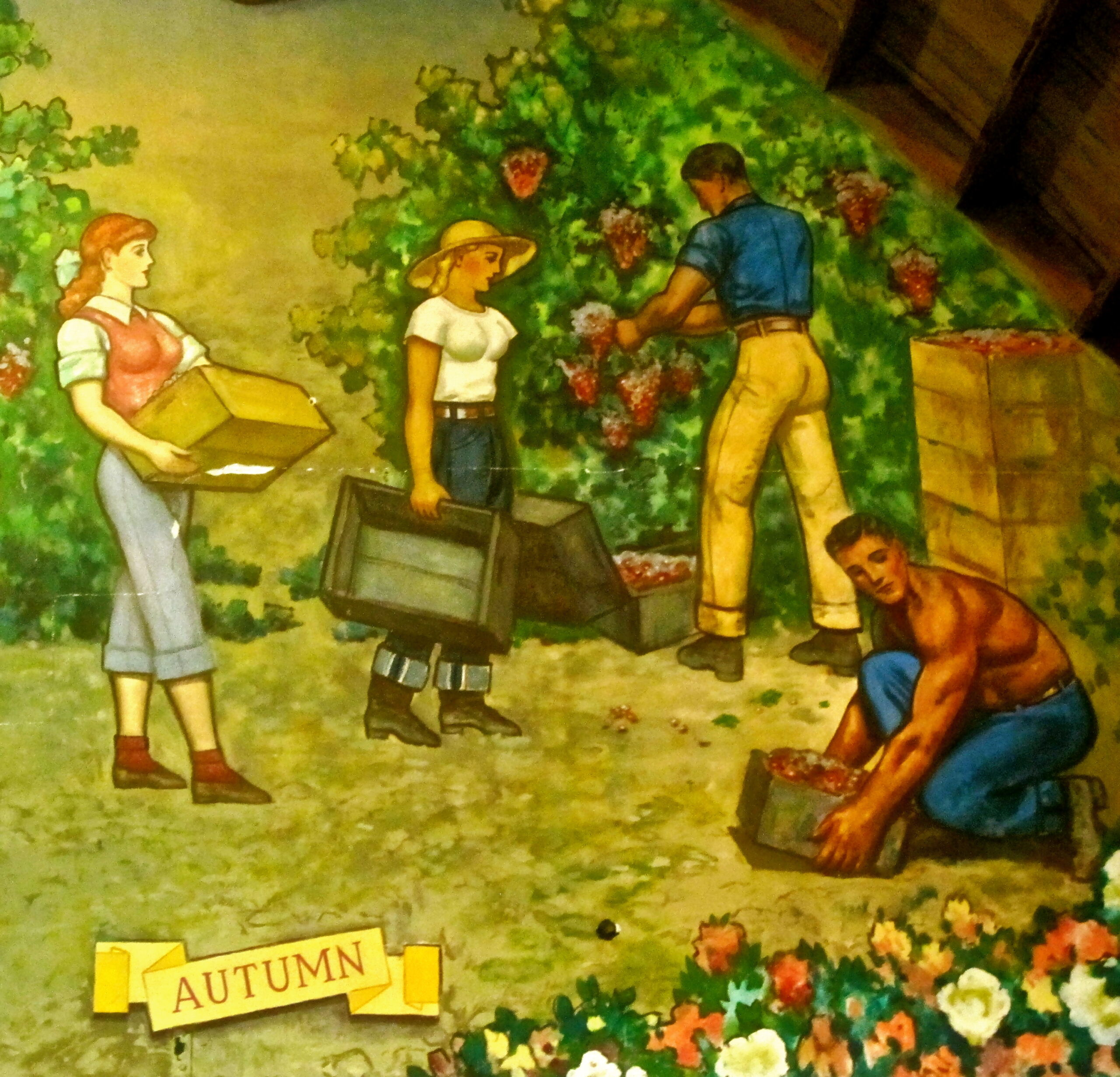 People harvesting grapes in a vineyard during autumn, with colorful flowers and lush grapevines.