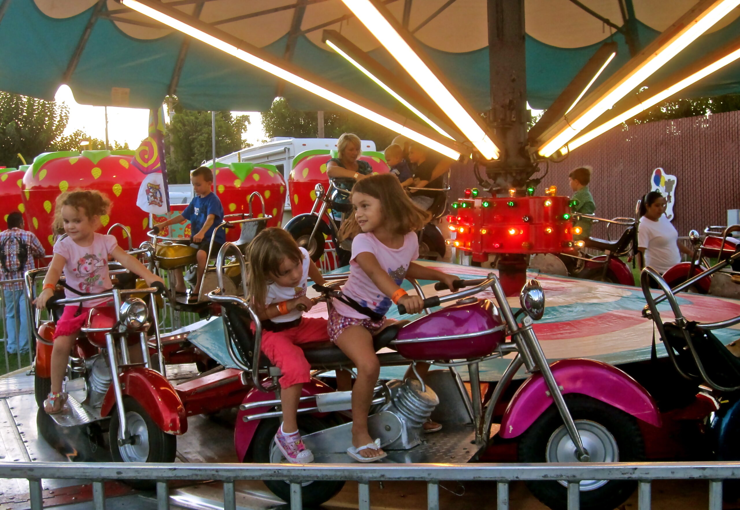 Children enjoying a ride on a colorful amusement park carousel at Lodi Winegrape Festival.