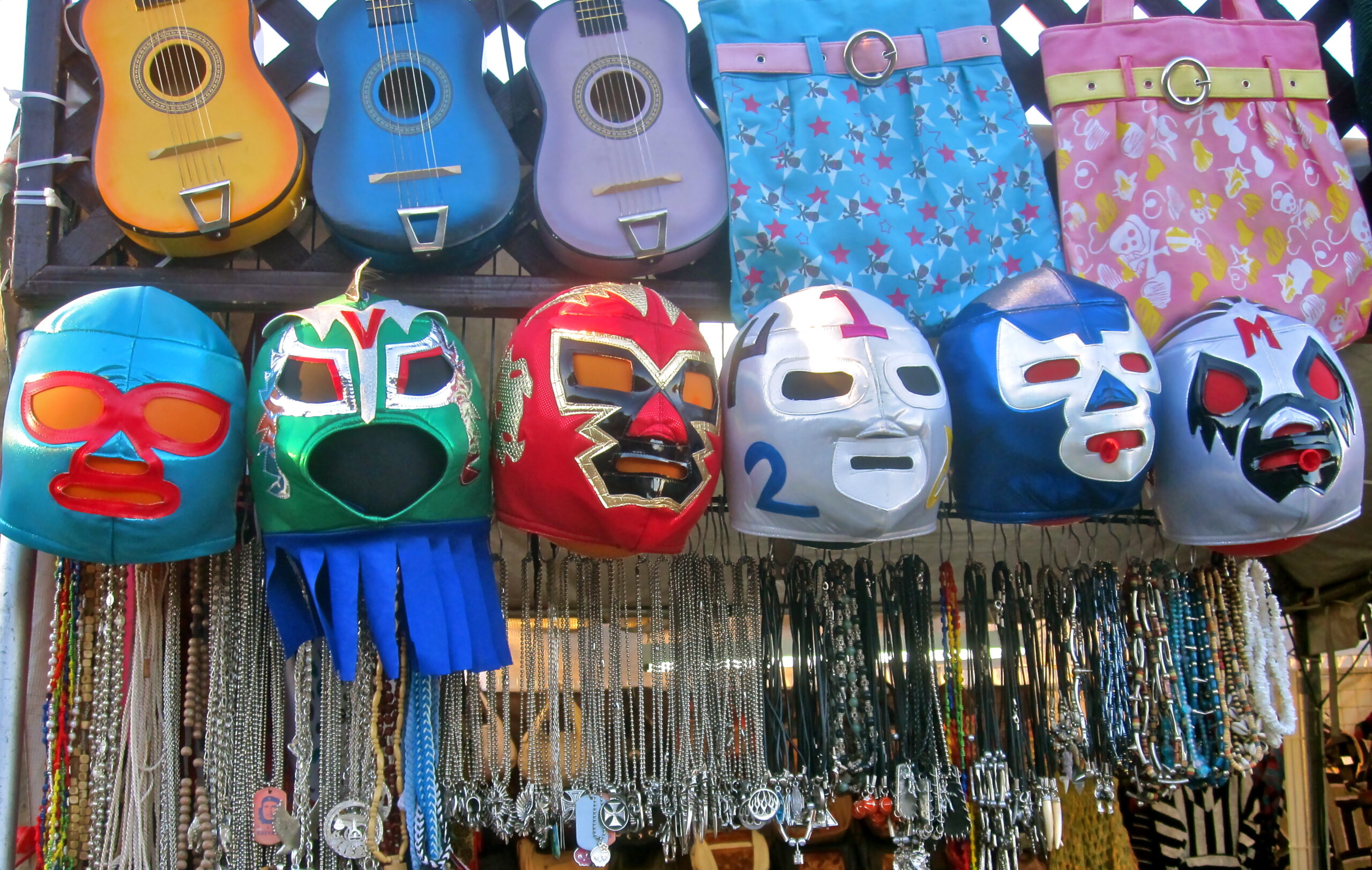 Vibrant display of Mexican masks and miniature guitars at a market stall.