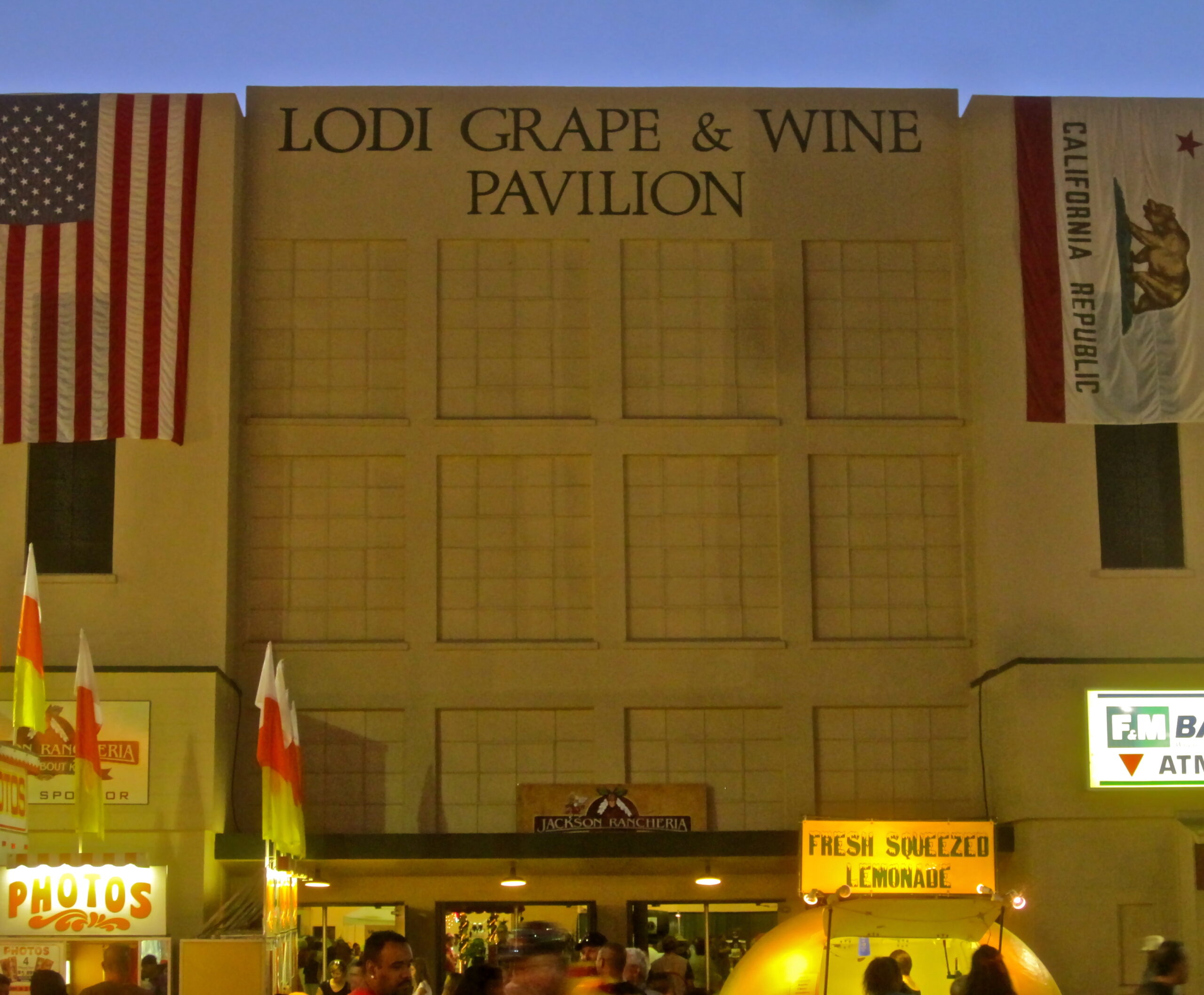 Lodi Grape & Wine Pavilion with empty display grids and California flags at night.