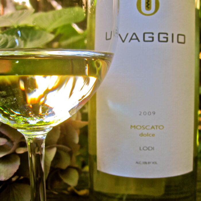 Close-up of a 2009 Moscato Dolce wine bottle from Lodi with a glass of white wine in the foreground.
