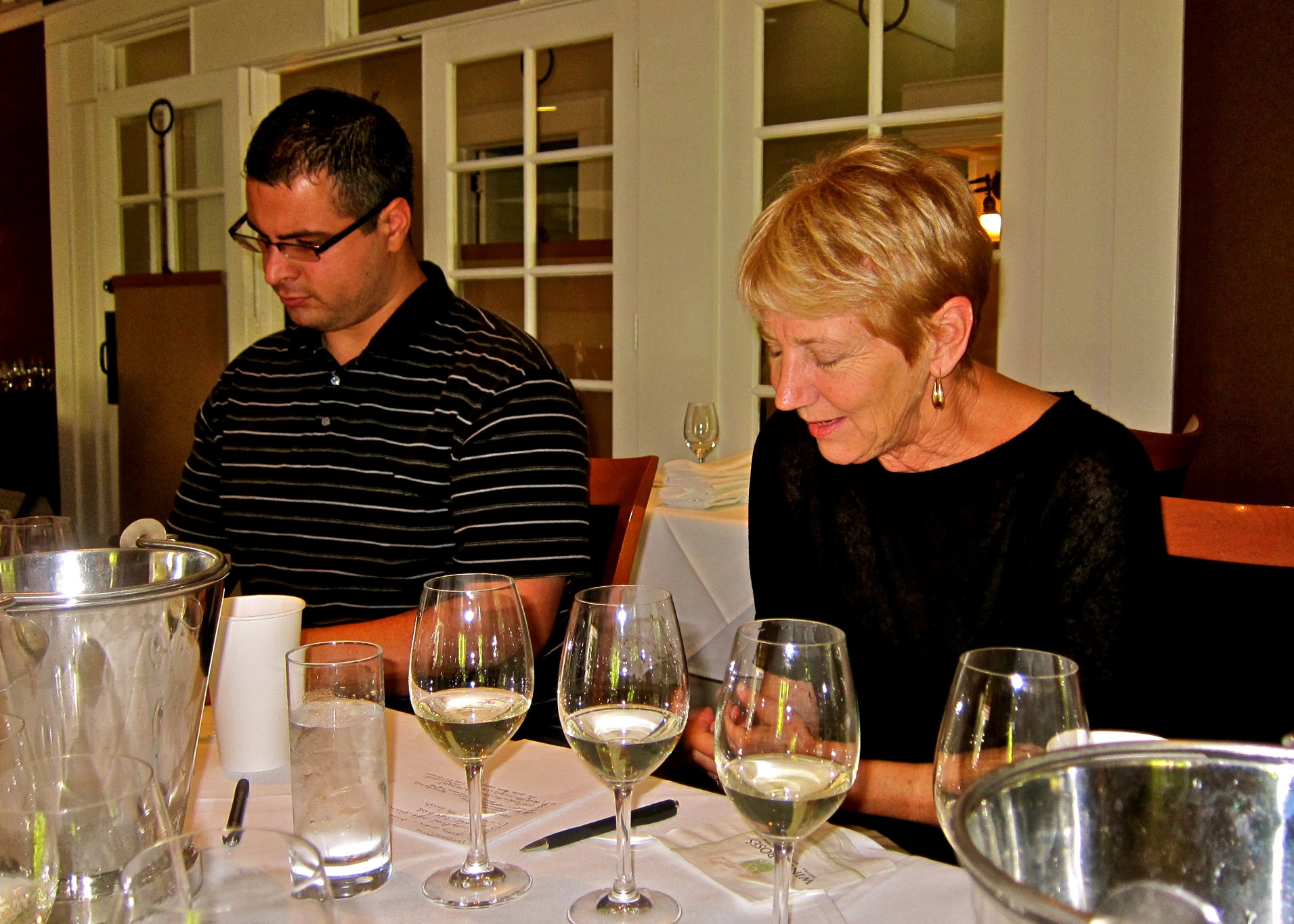 Two people tasting white wine at a Lodi wine tasting event, with wine glasses and tasting setup.