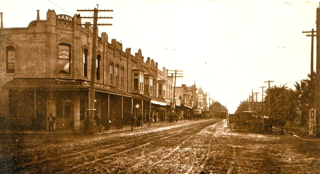 Vintage photo of Lodi's historic downtown with old buildings, dirt road, and early 20th-century streetcars.