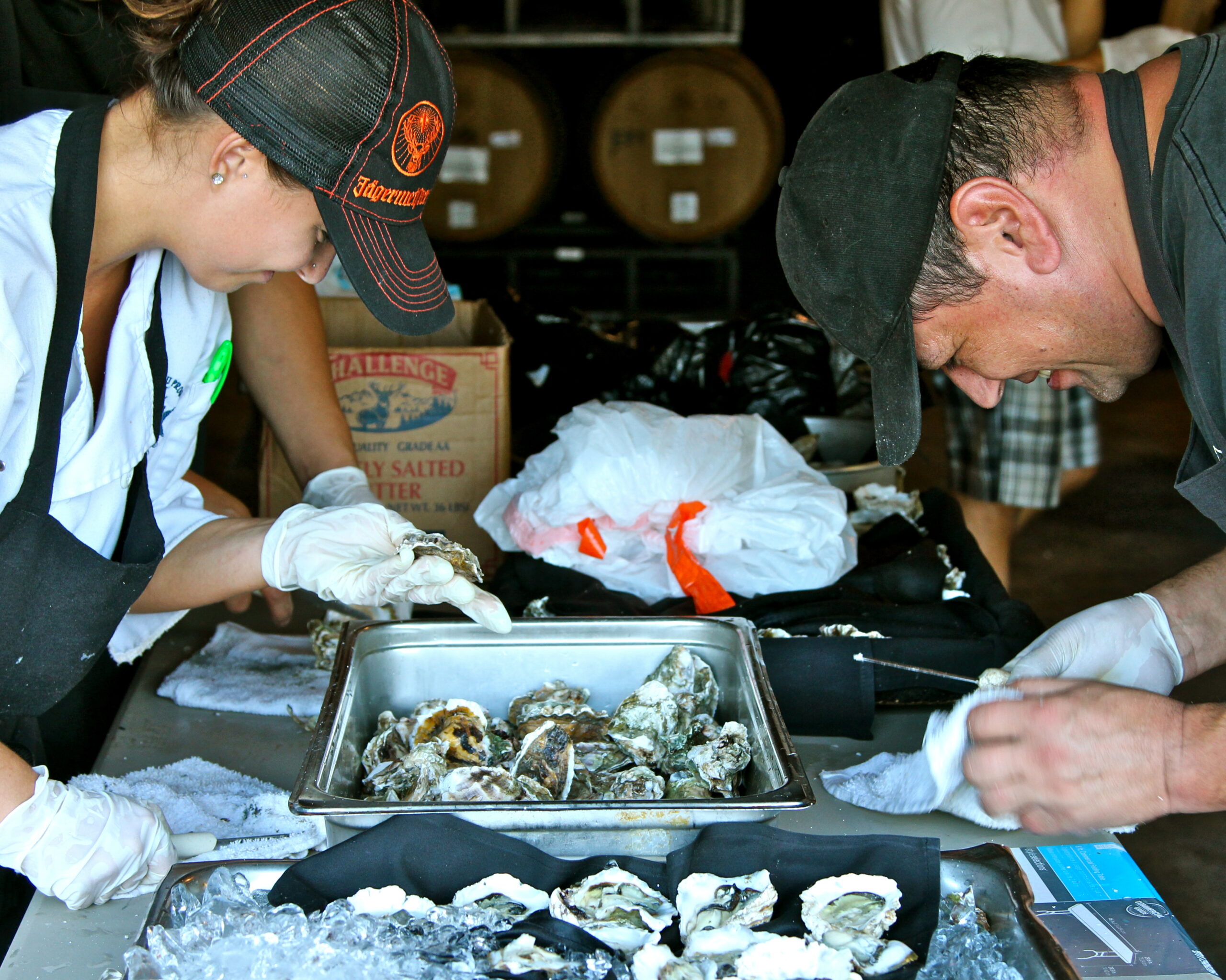 People tasting and preparing oysters at a Lodi Winegrape Commission event in a winery setting.