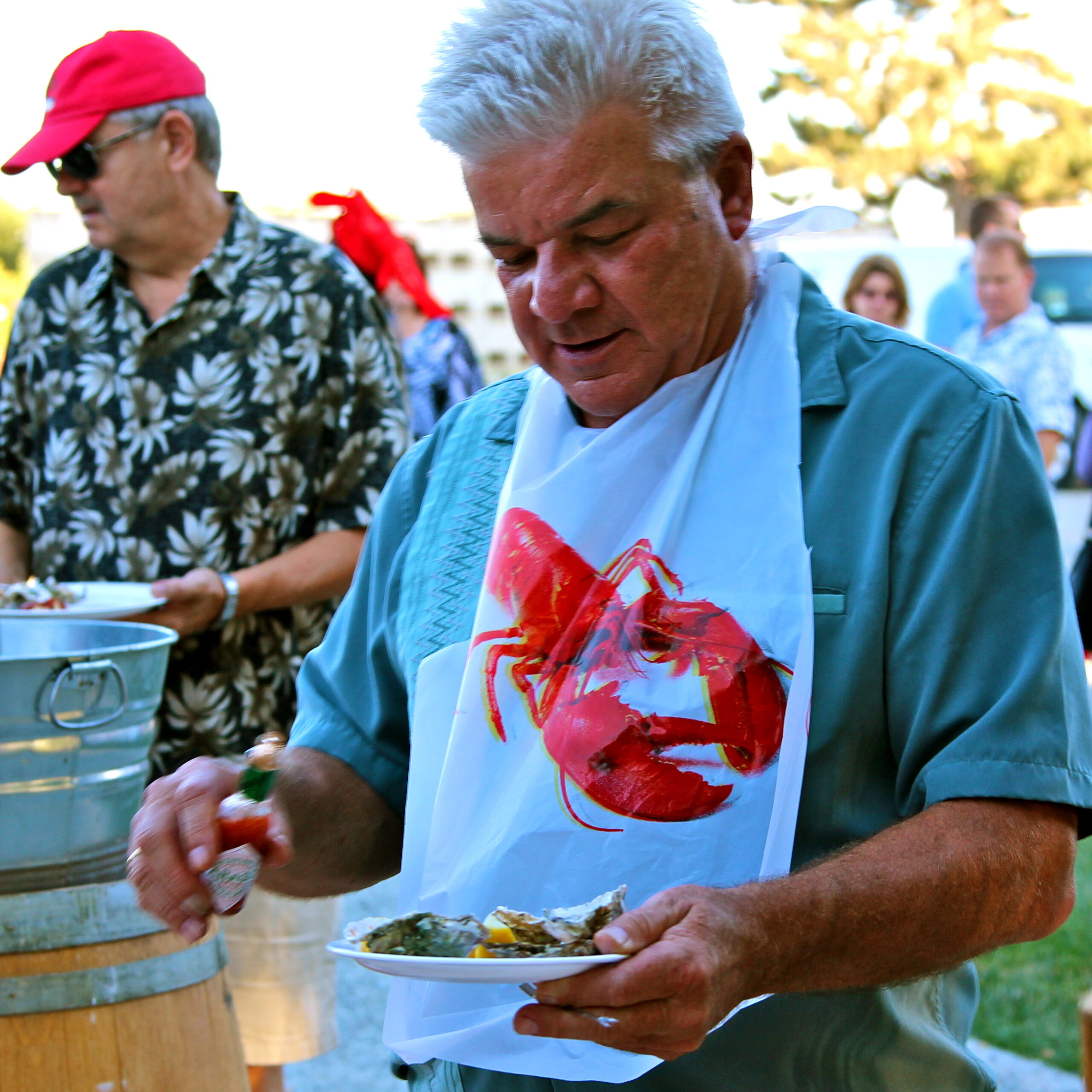 Man at Lodi Winegrape Commission event holding a plate of food with a lobster bib.