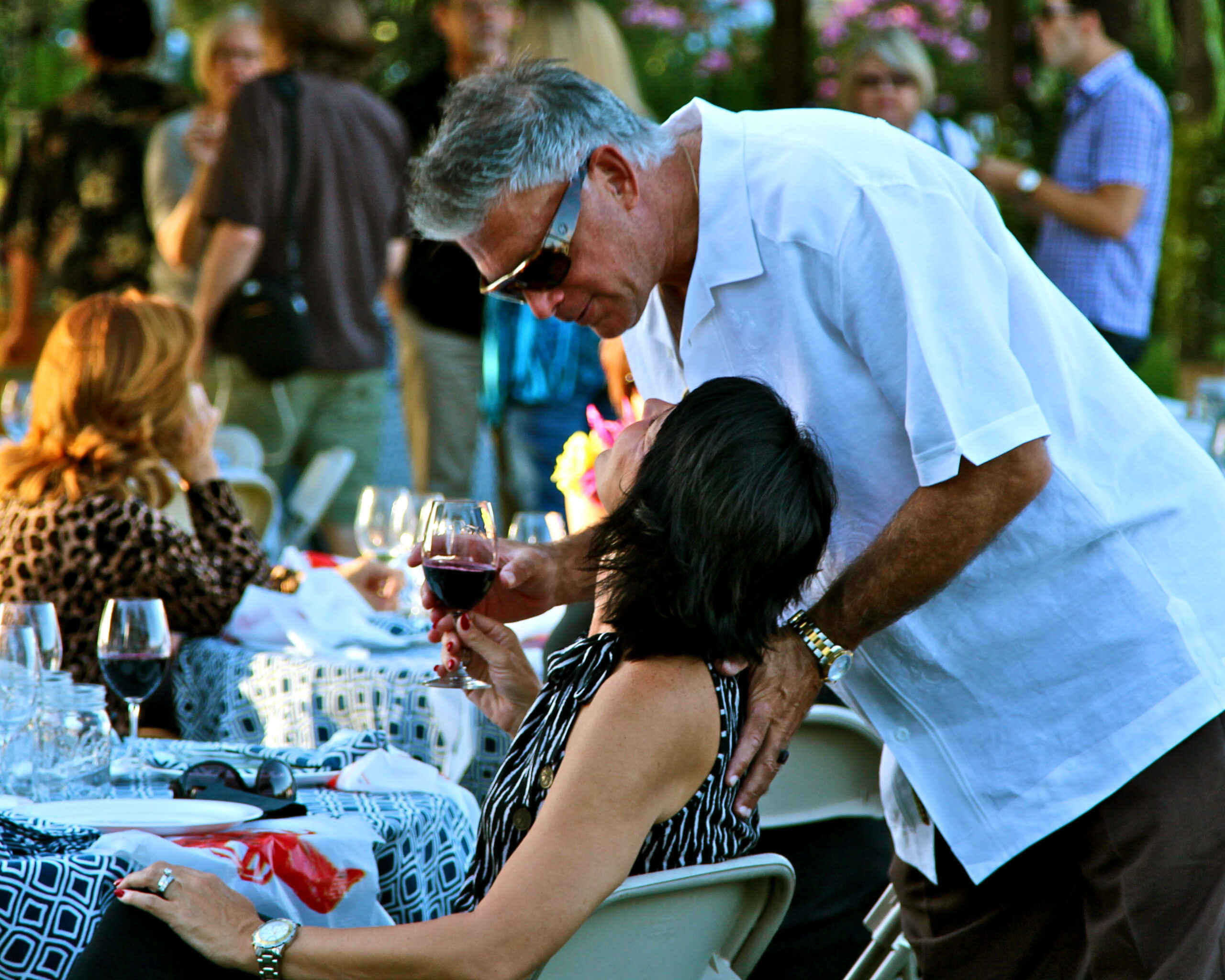 Man offering wine to woman at outdoor wine tasting event in Lodi, California.