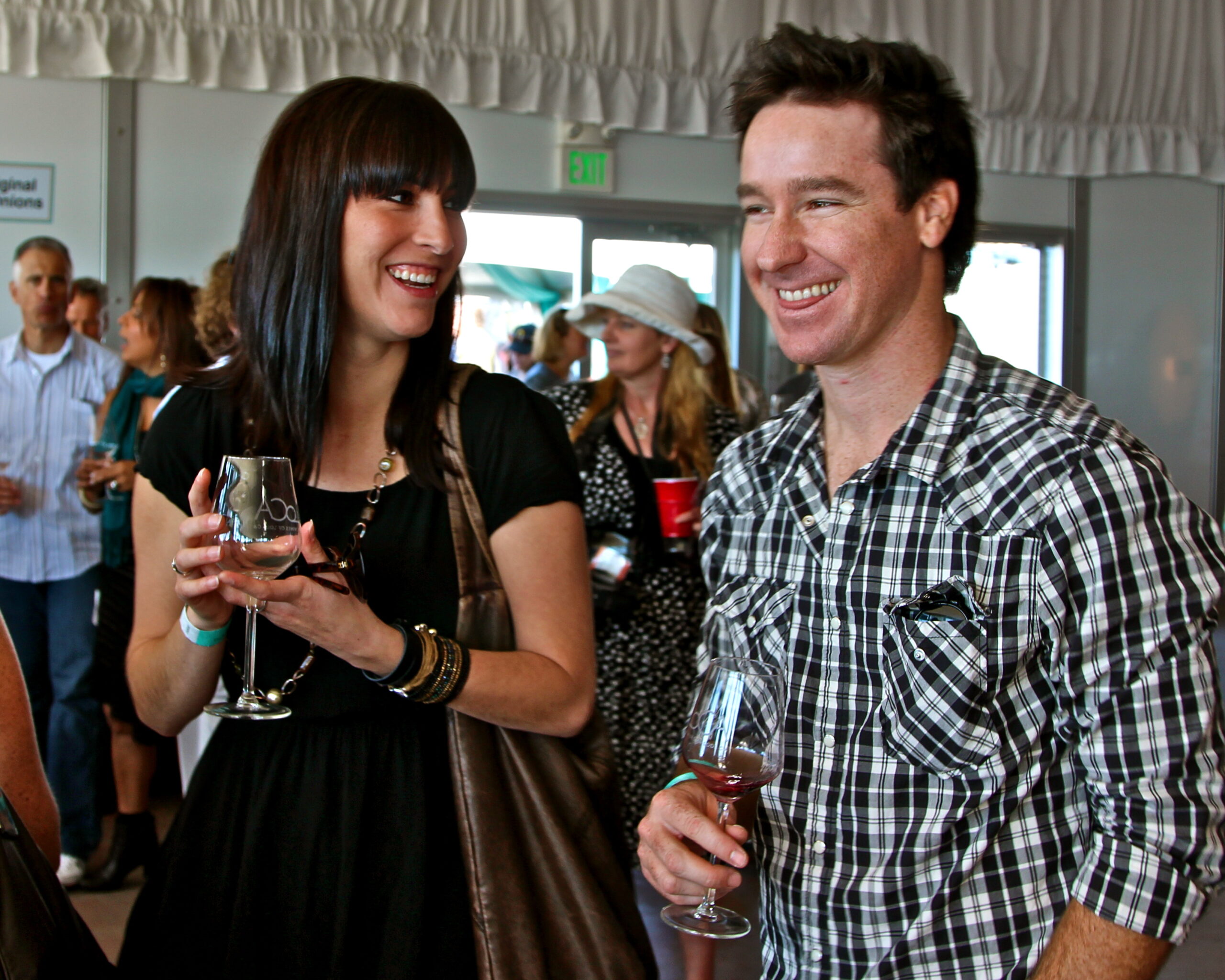 People enjoying wine at a Lodi Winegrape Commission event, smiling and socializing indoors.