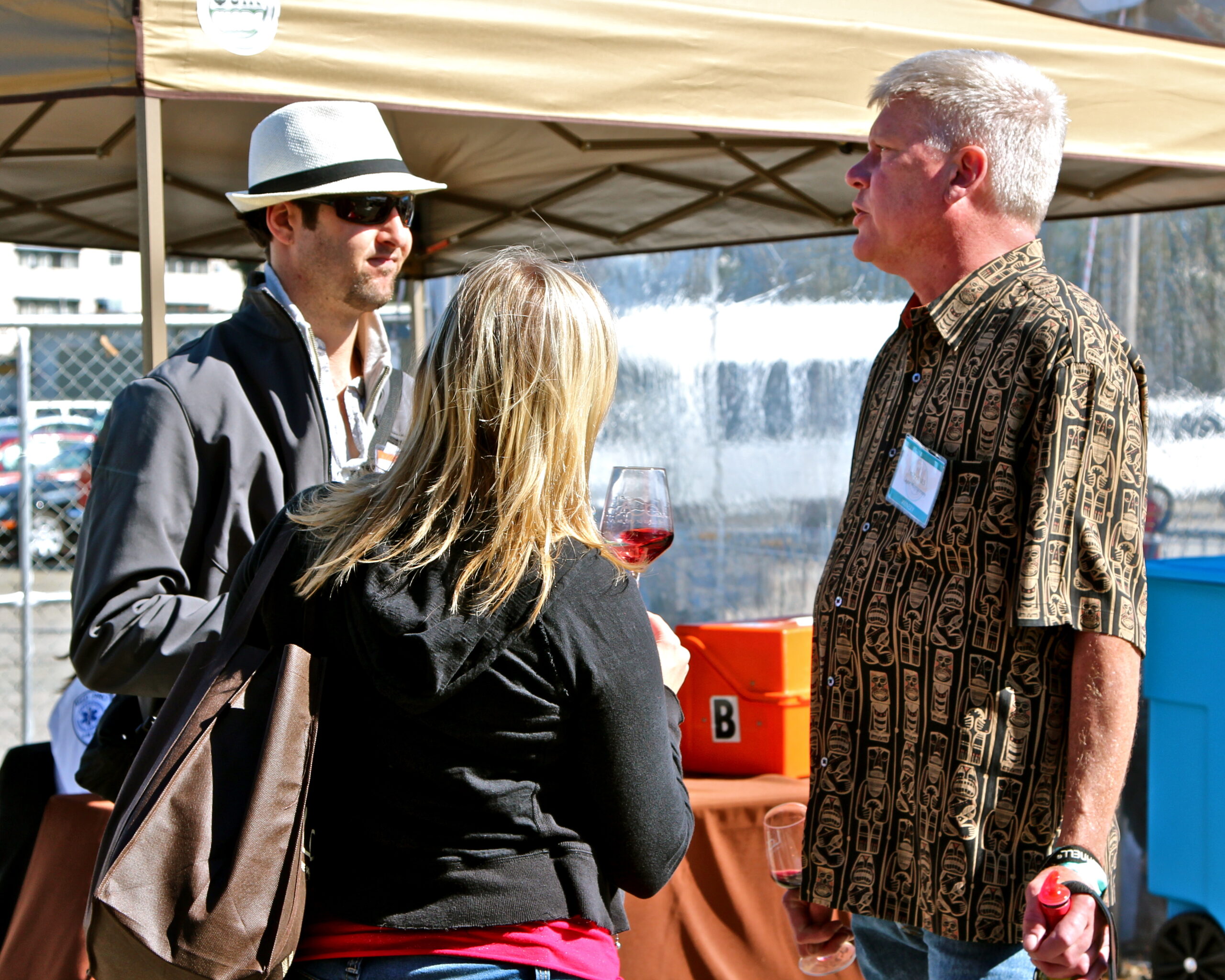 People tasting wine at a Lodi Winegrape Commission outdoor event with a water fountain in the background.