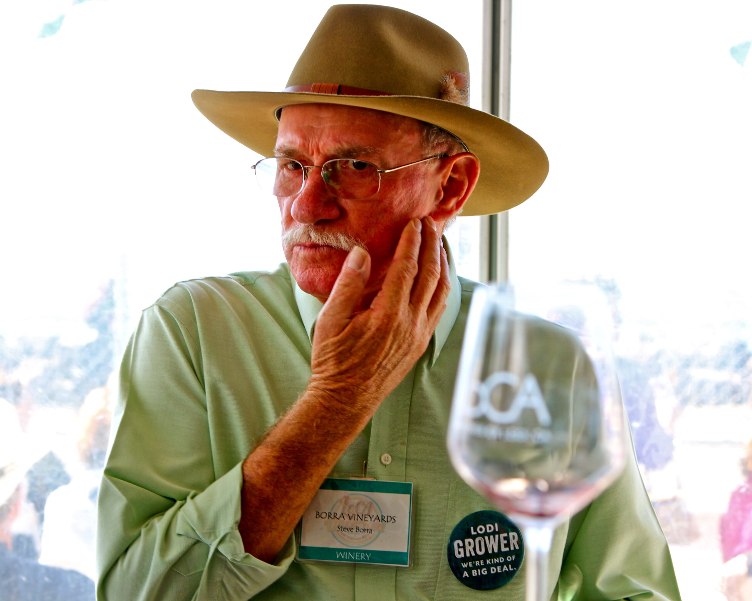 Elderly man with a hat tasting wine at a Lodi wine event, showcasing local wine industry.