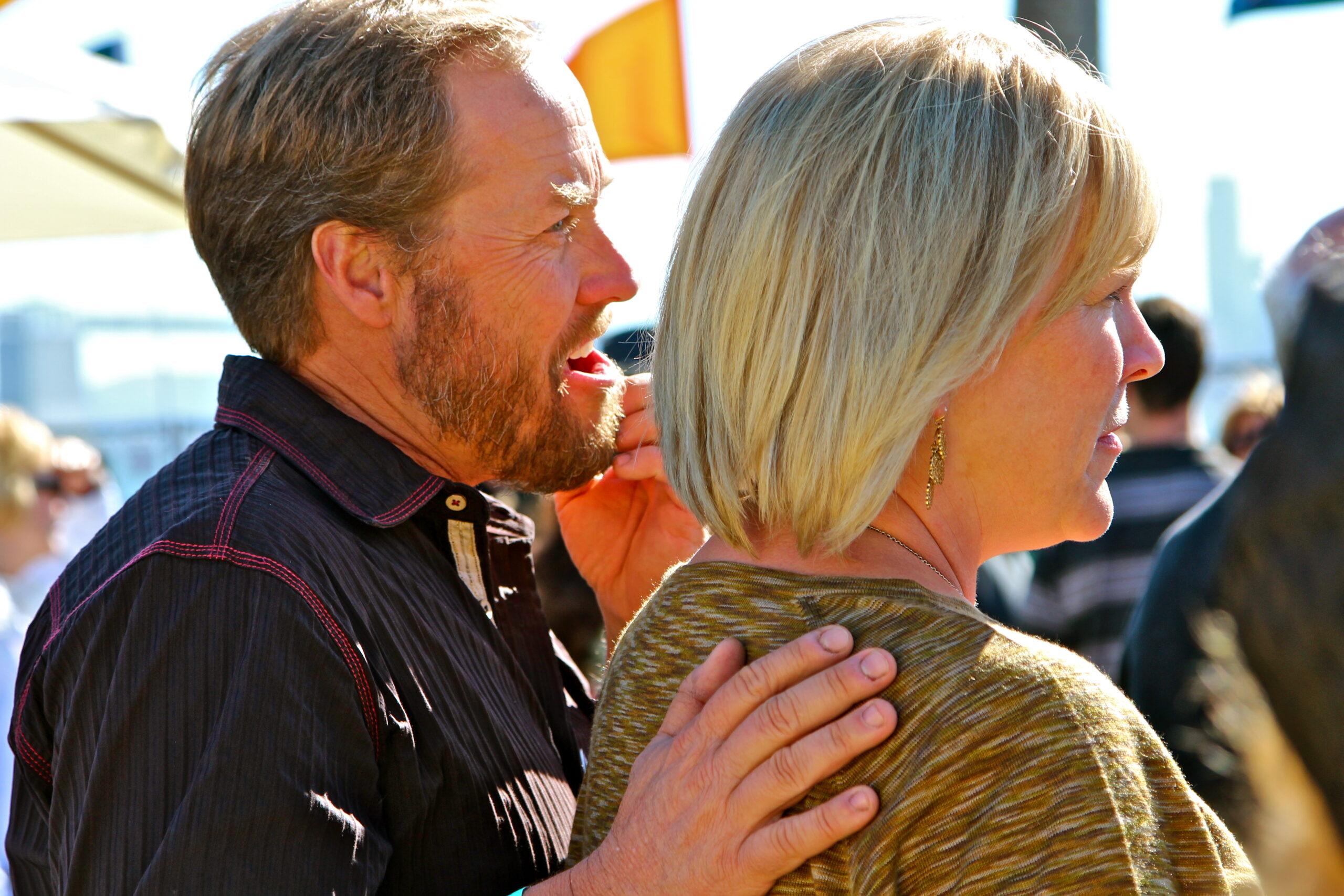 Two people at a Lodi wine event, engaging in conversation with a vineyard background.