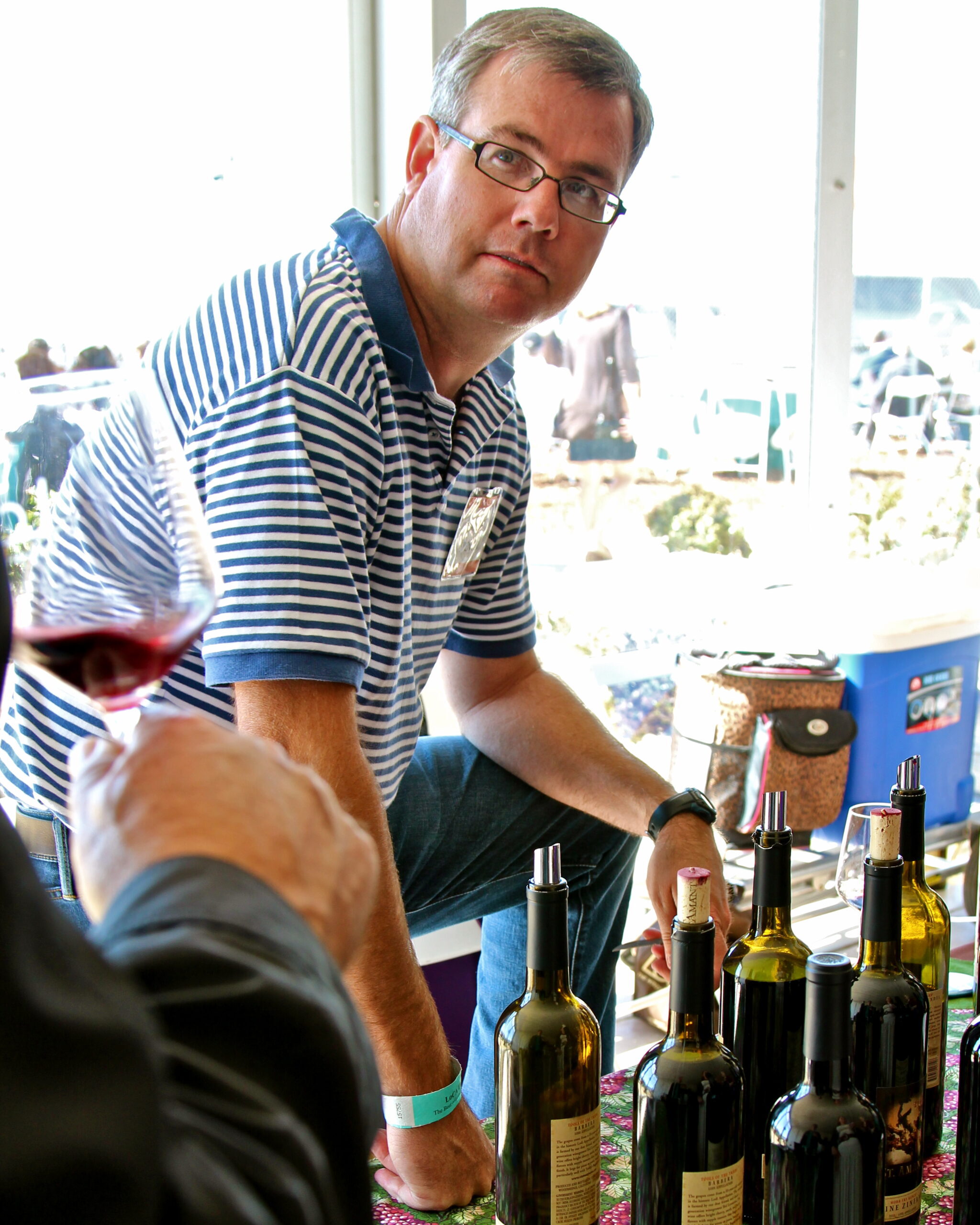 Man at wine tasting event with bottles of wine on table, promoting Lodi winegrapes and local wine industry.