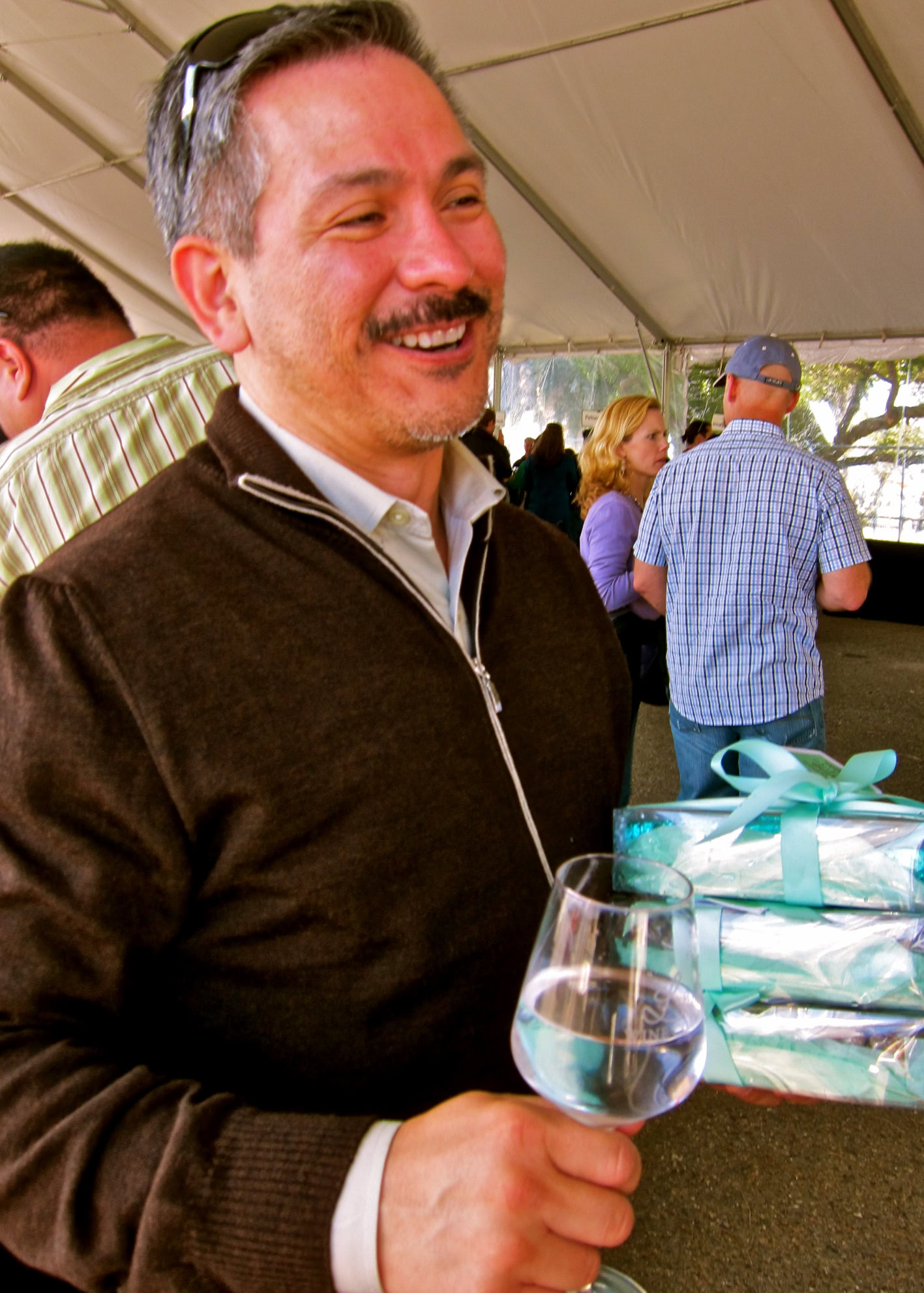 Smiling man holding a glass of white wine at a wine tasting event in Lodi, California.