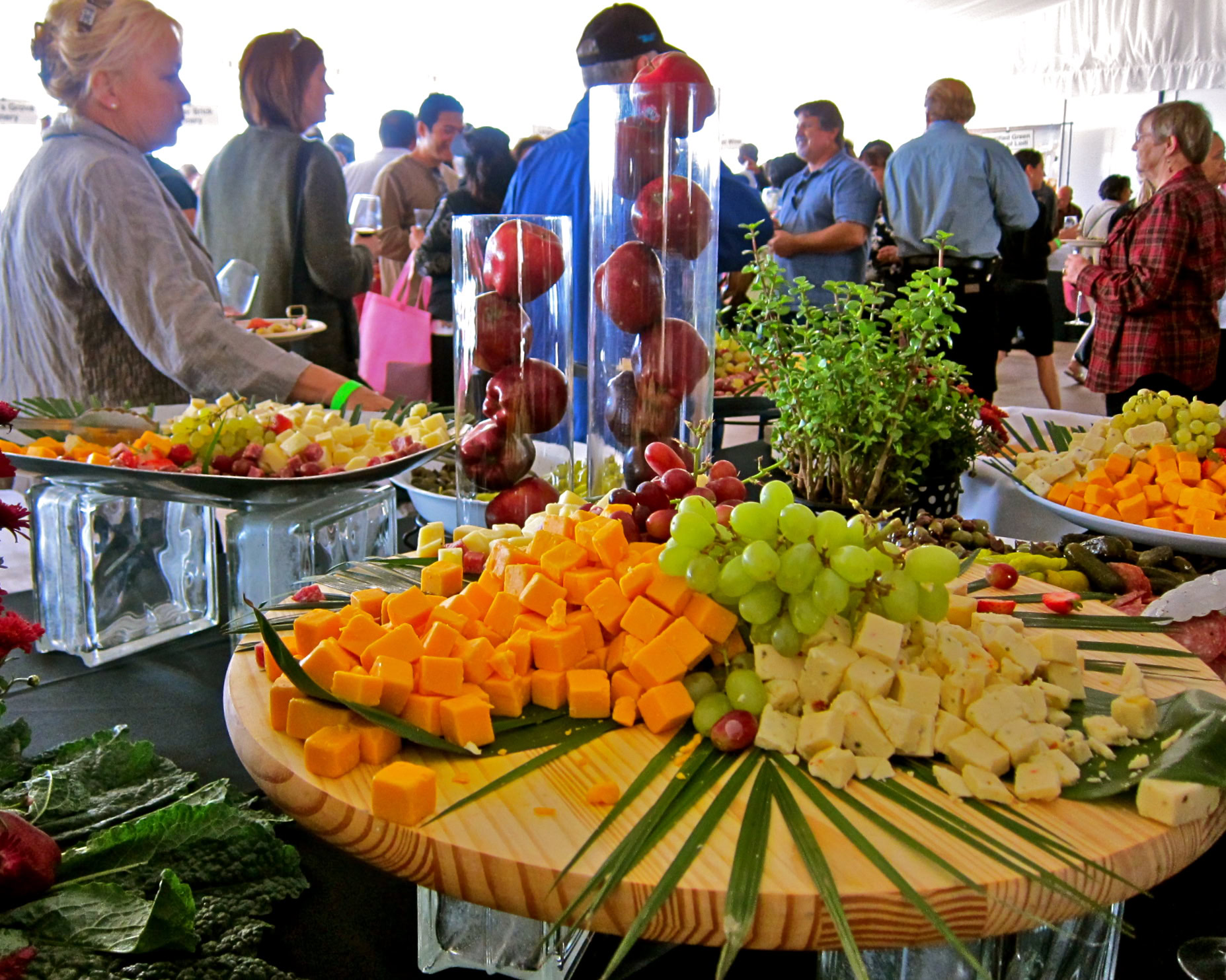 Lodi Winegrape Commission event with cheese, grapes, and fresh herbs on display, attendees in background.