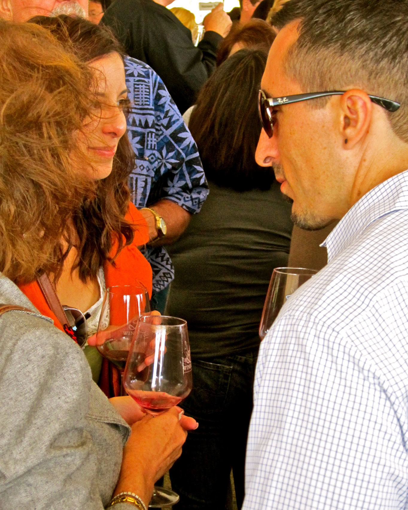 Two people enjoying wine at a social event, engaging in conversation with wine glasses in hand.