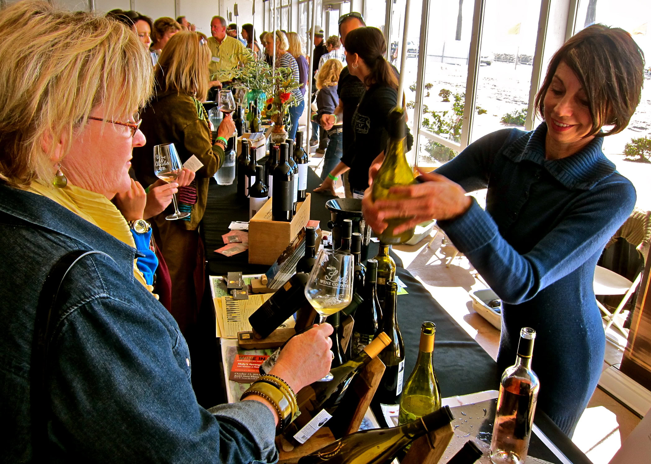 People tasting and purchasing Lodi wine at a wine tasting event in a bright, modern venue.