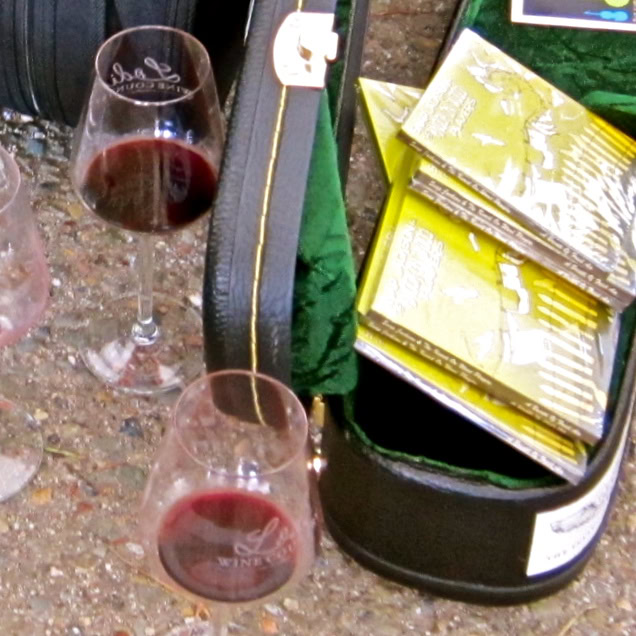 Two glasses of red wine on a table with brochures and a wine bag at Lodi Winegrape Commission event.
