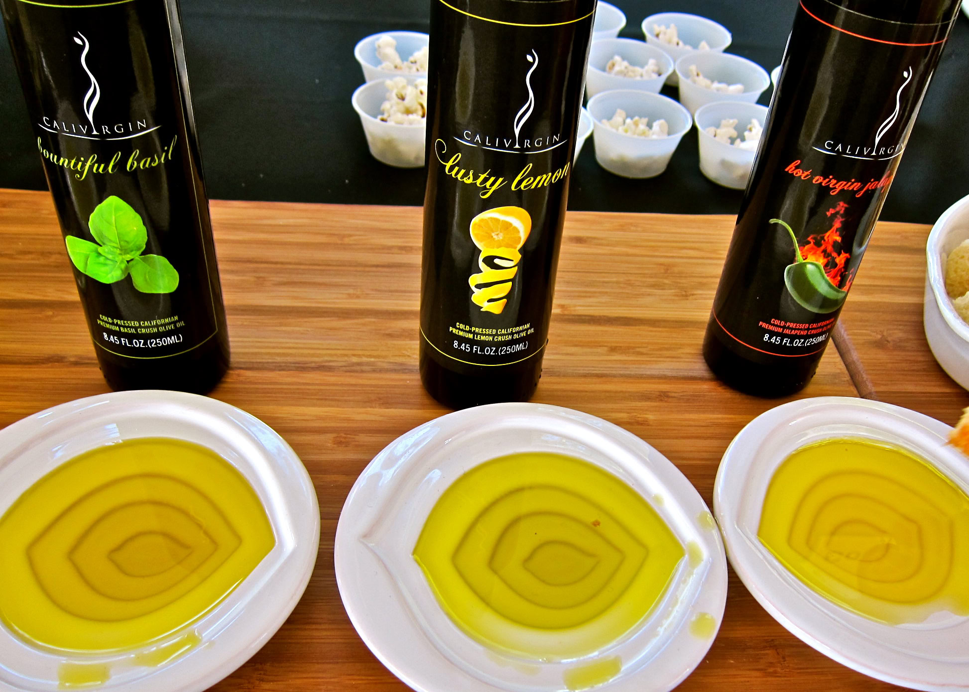 Lodi wine tasting setup with three bottles of Calivirgin olive oil and three plates of olive oil samples.