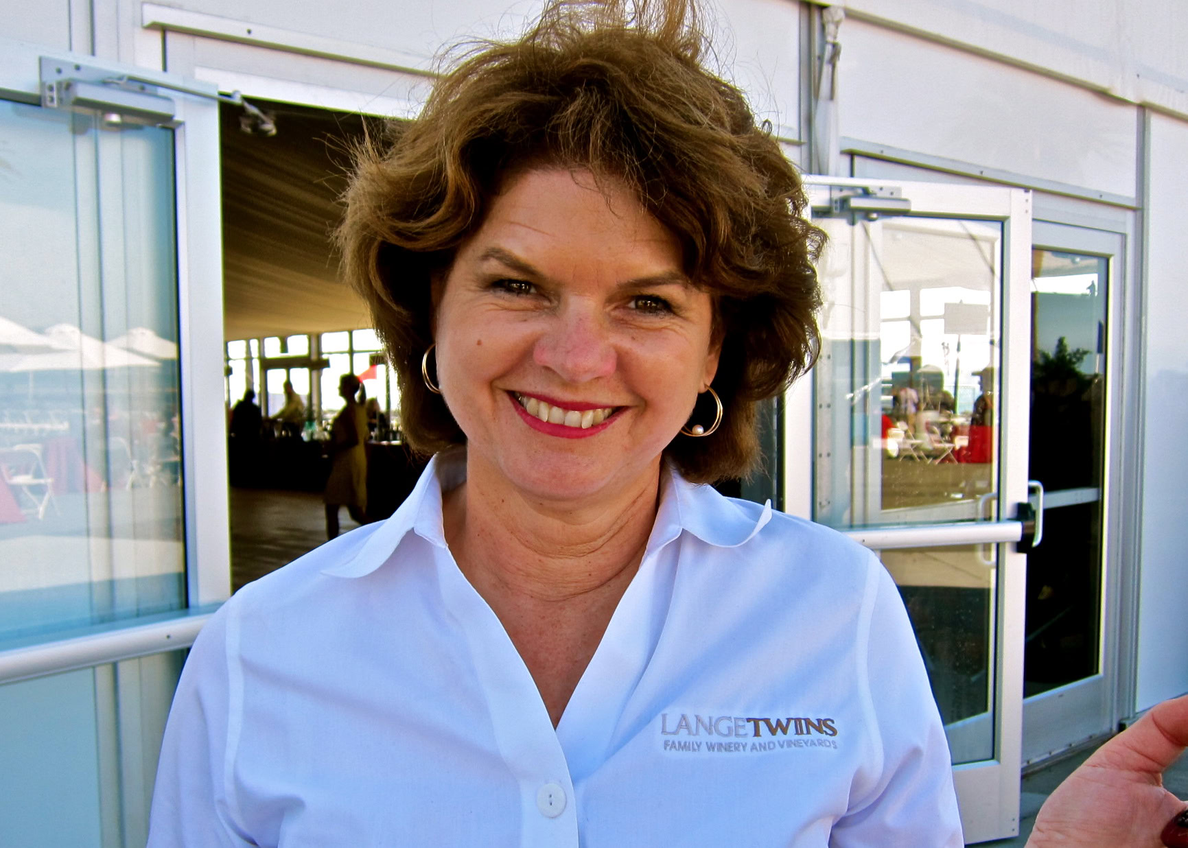 Smiling woman in white shirt at Lodi Winegrape Commission event, outdoor setting, sunny day.