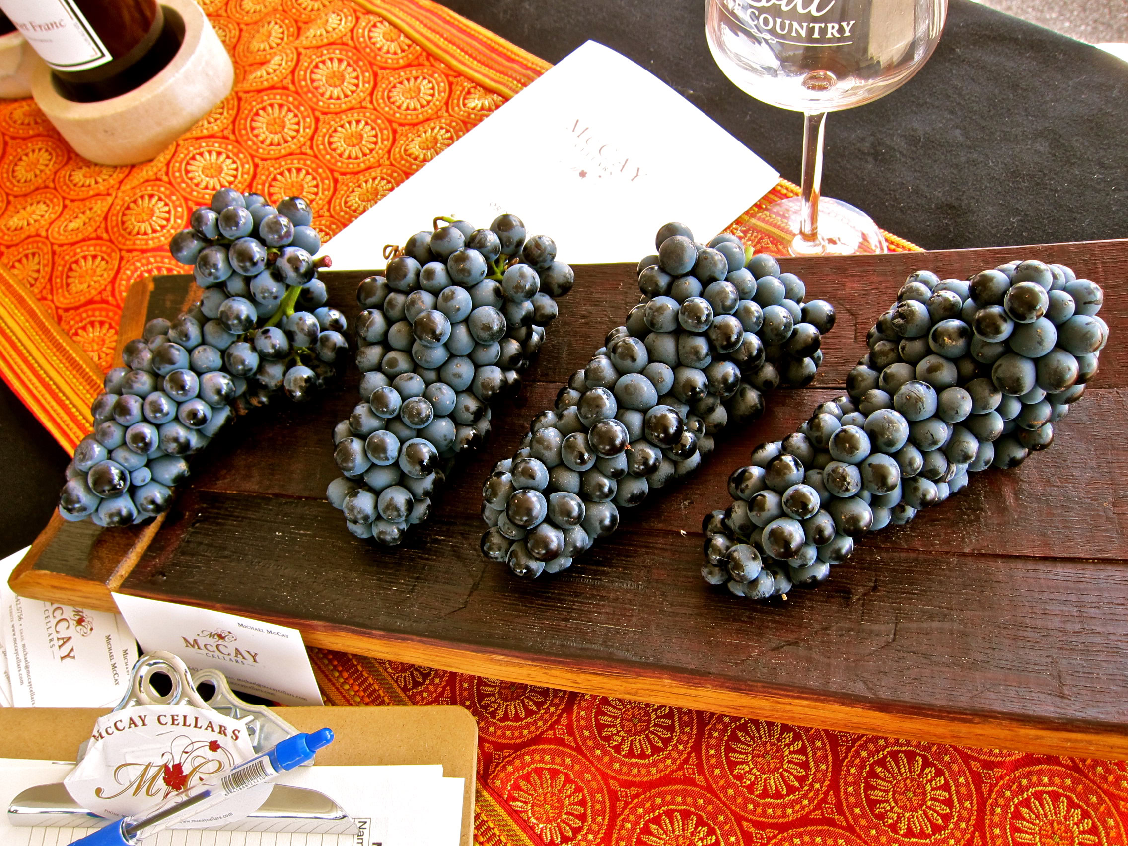 Four clusters of ripe Lodi winegrapes on a wooden board at a wine tasting event.