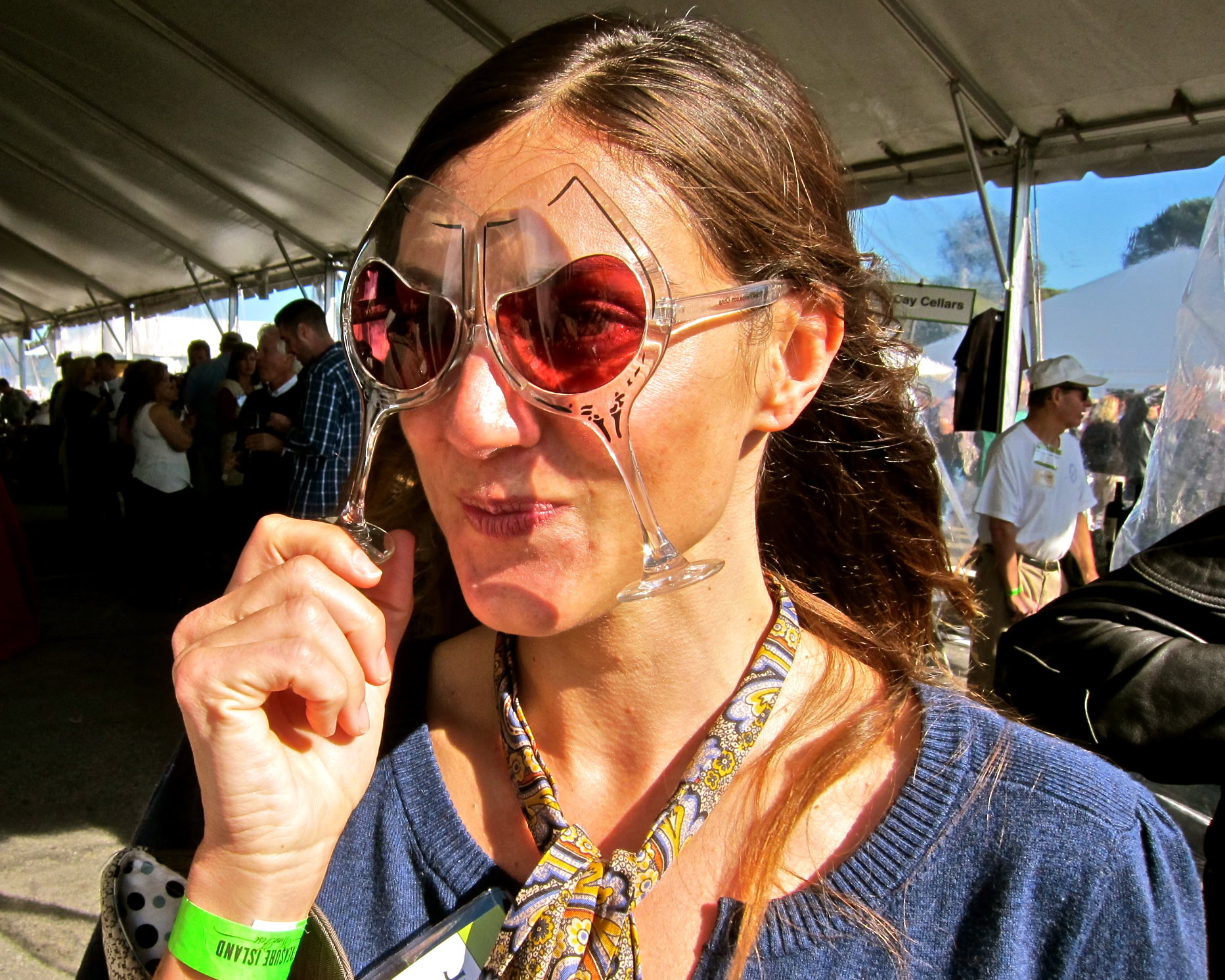 Woman tasting wine at Lodi Winegrape Commission event, wearing sunglasses and a blue sweater.