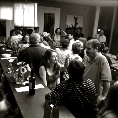 People gathered at a Lodi Winegrape Commission event, engaging in conversation and wine tasting.