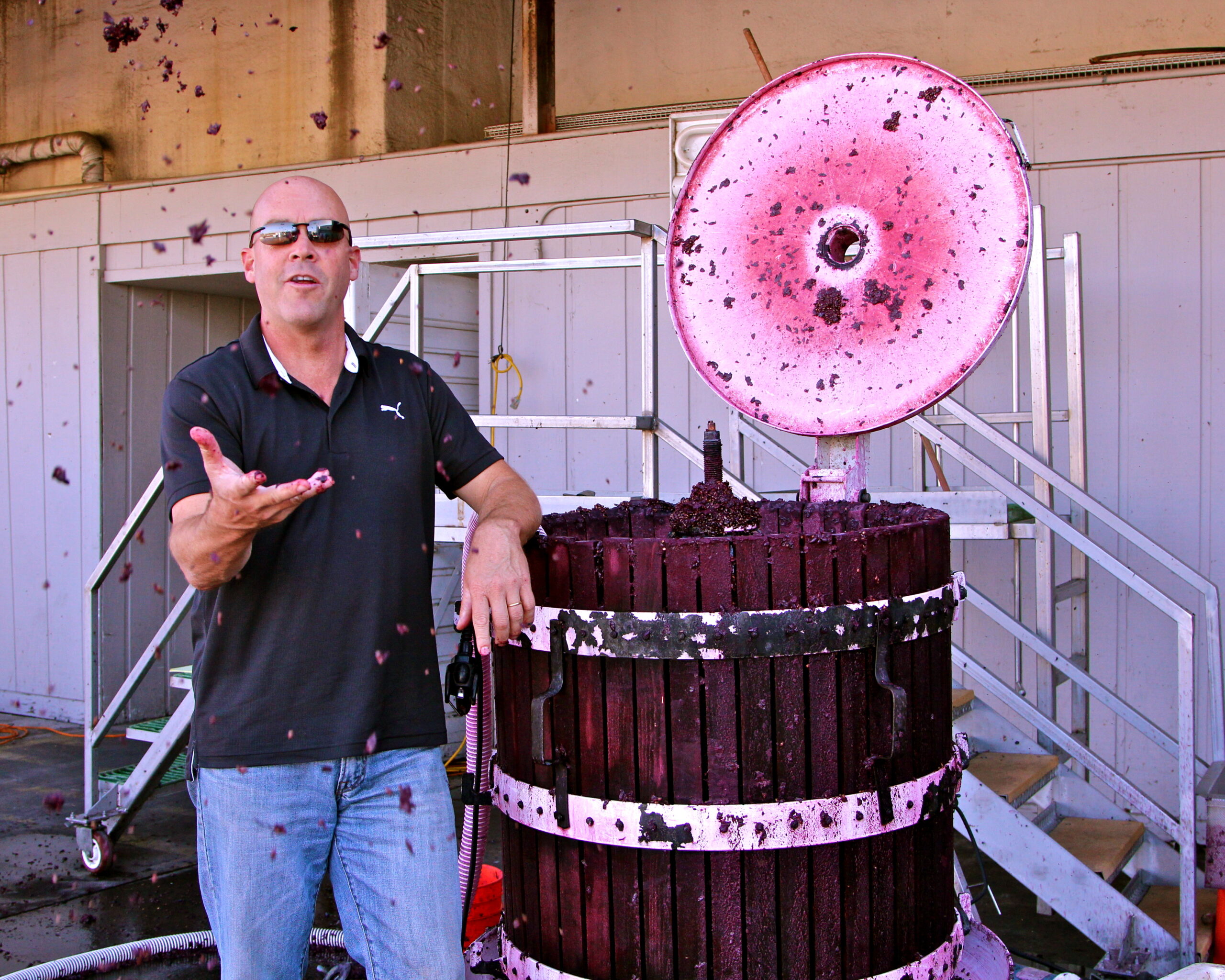 Winemaker explaining grape crushing process at Lodi wine region with grape juice splashing.