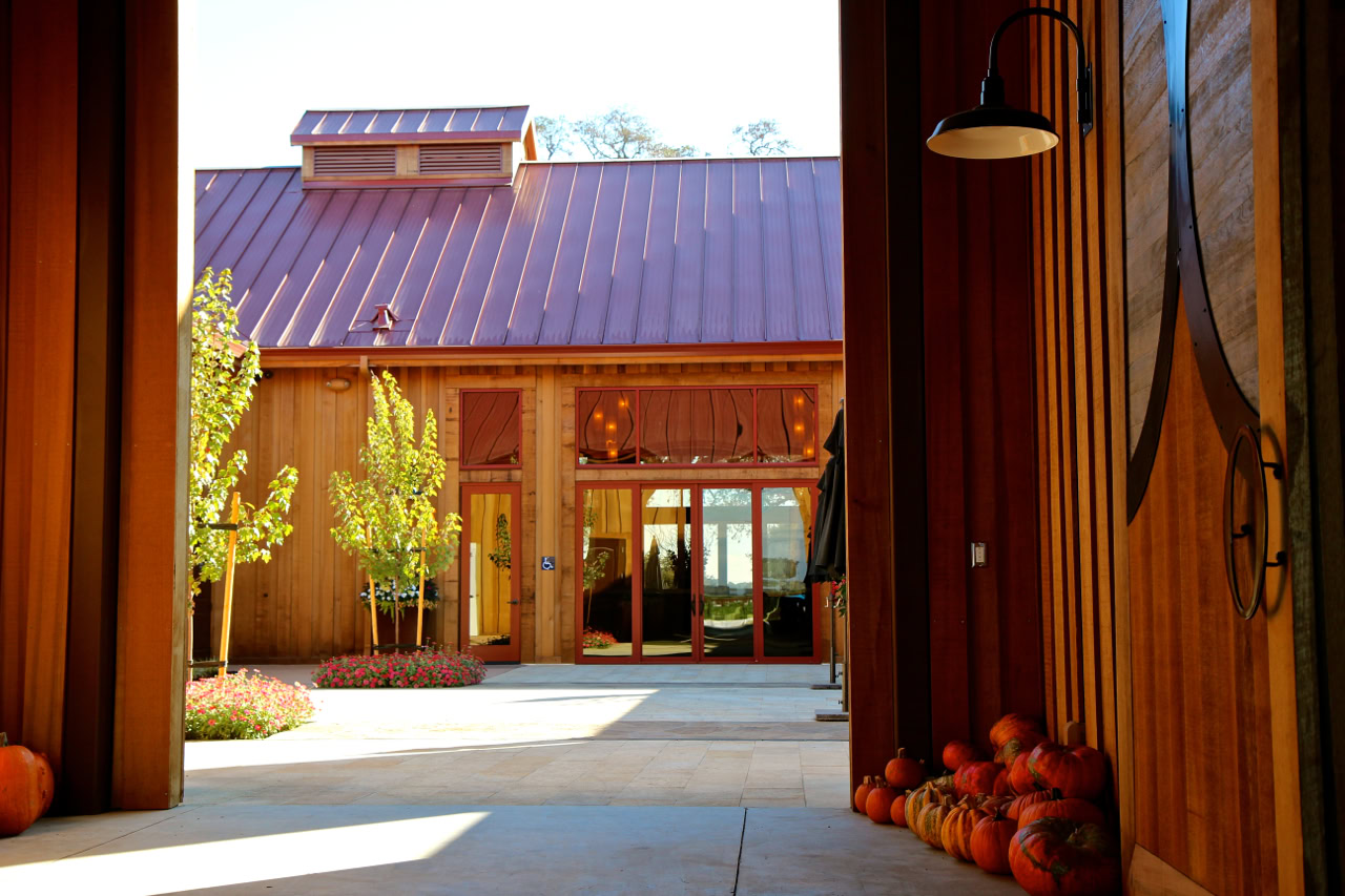 Entrance of a winery with wooden architecture, pumpkins, and grapevines in Lodi, California.